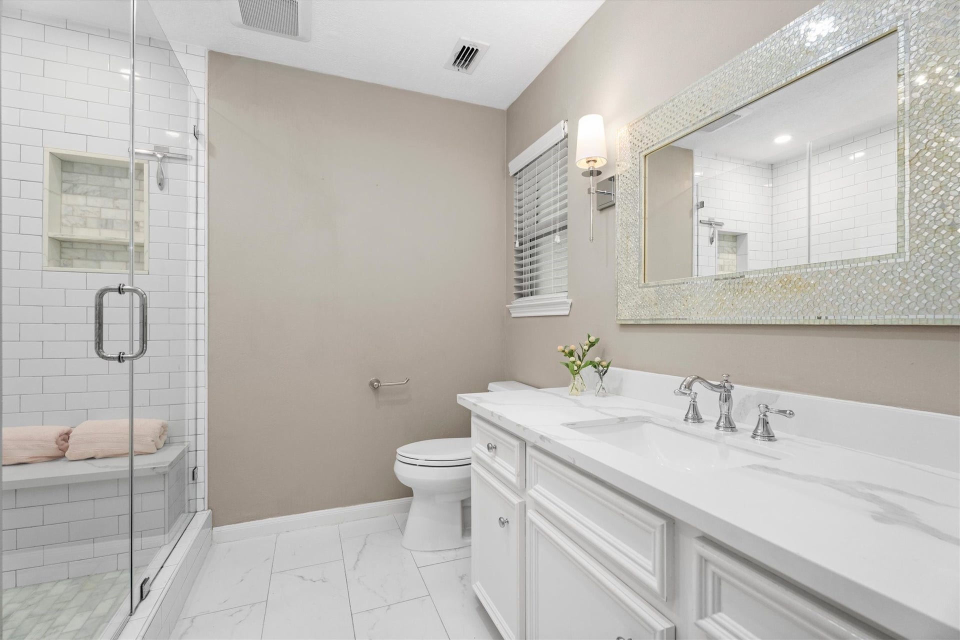 This bathroom is a dream! Updated vanity, lighting, tile, fixtures, and a large, glass-enclosed shower with bench.