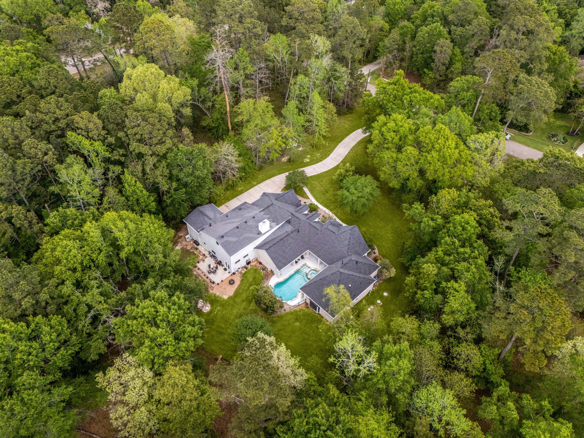 11956 White Oak Crossing, Conroe, TX 77385 The wooded surrounding maintains privacy. The square patio pad in this photo is for the Guest House.
