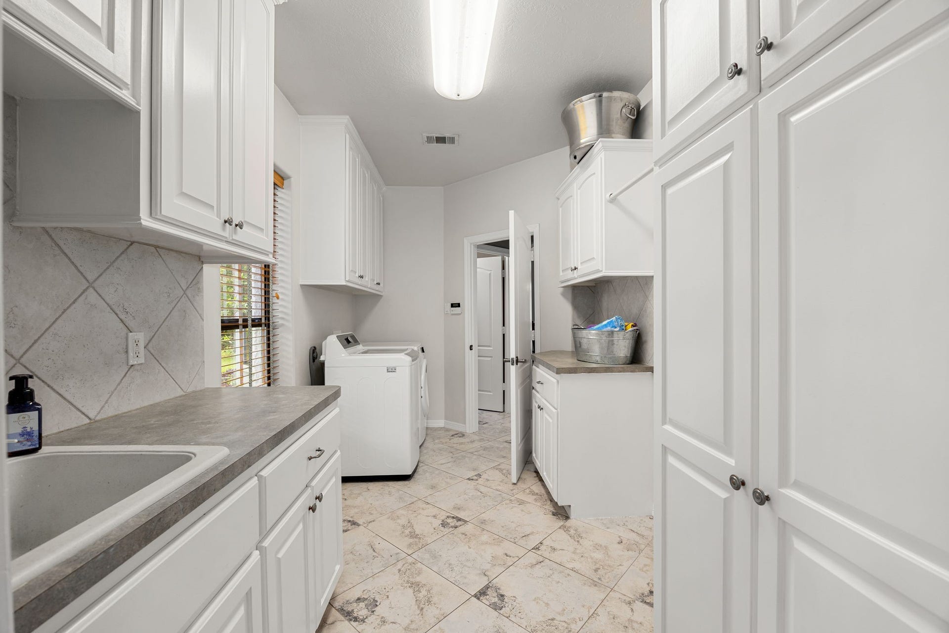 11956 White Oak Crossing, Conroe, TX 77385 This laundry room features a convenient utility sink, ample cabinetry for storage, and direct access to the garage.