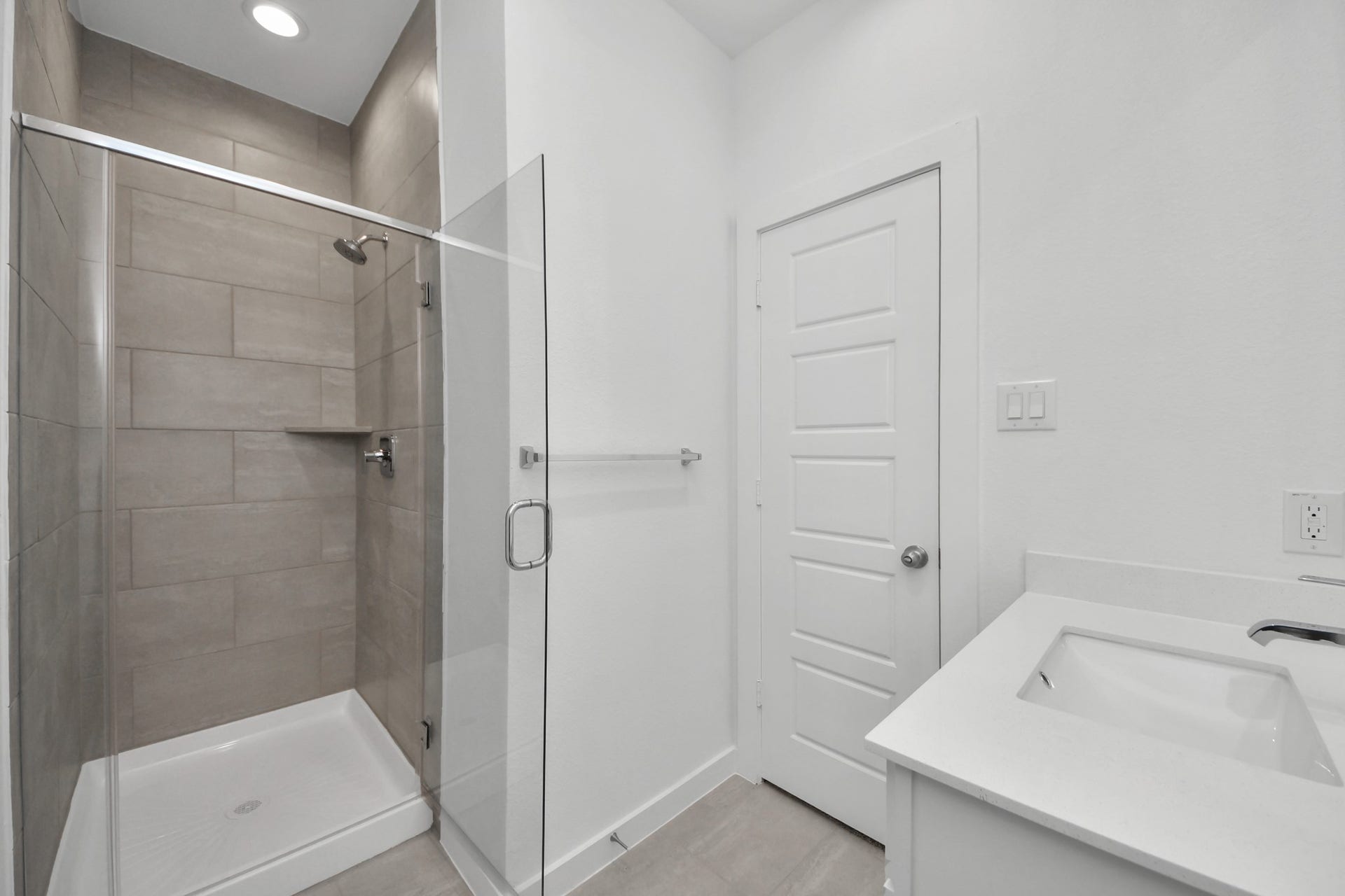 Secondary bath features tile flooring, walk-in shower with tile surround, light stained wood cabinets, beautiful light countertop. Sample photo of completed home with similar floor plan. Actual colors and selections may vary.