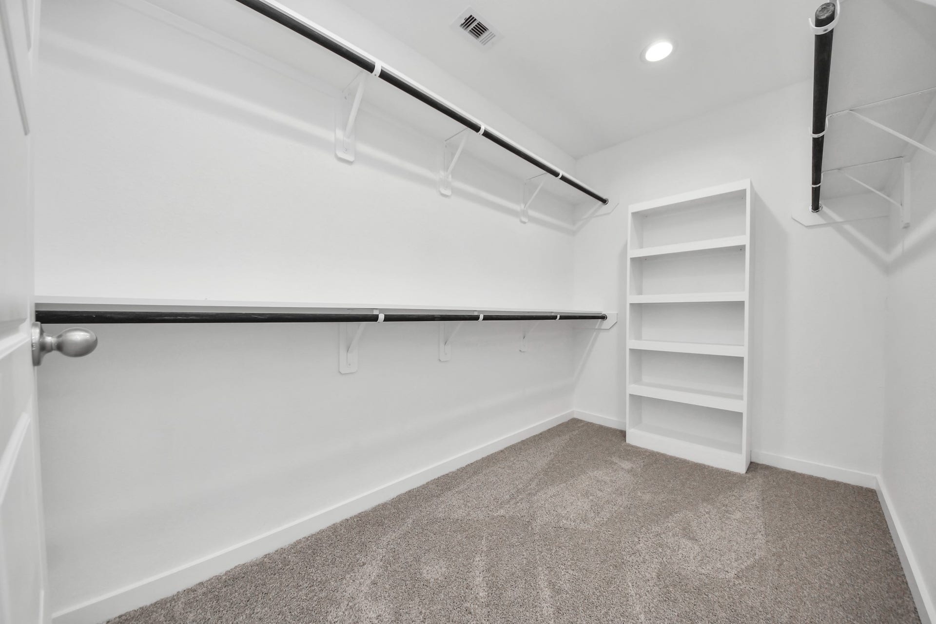 Walk-in closet that epitomizes luxury and practicality. This generously sized space features built-in shelving, offering abundant room for impeccable organization. High ceilings and recessed lighting create a bright and welcoming ambiance. Sample photo of completed home with similar floor plan. Actual colors and selections may vary.