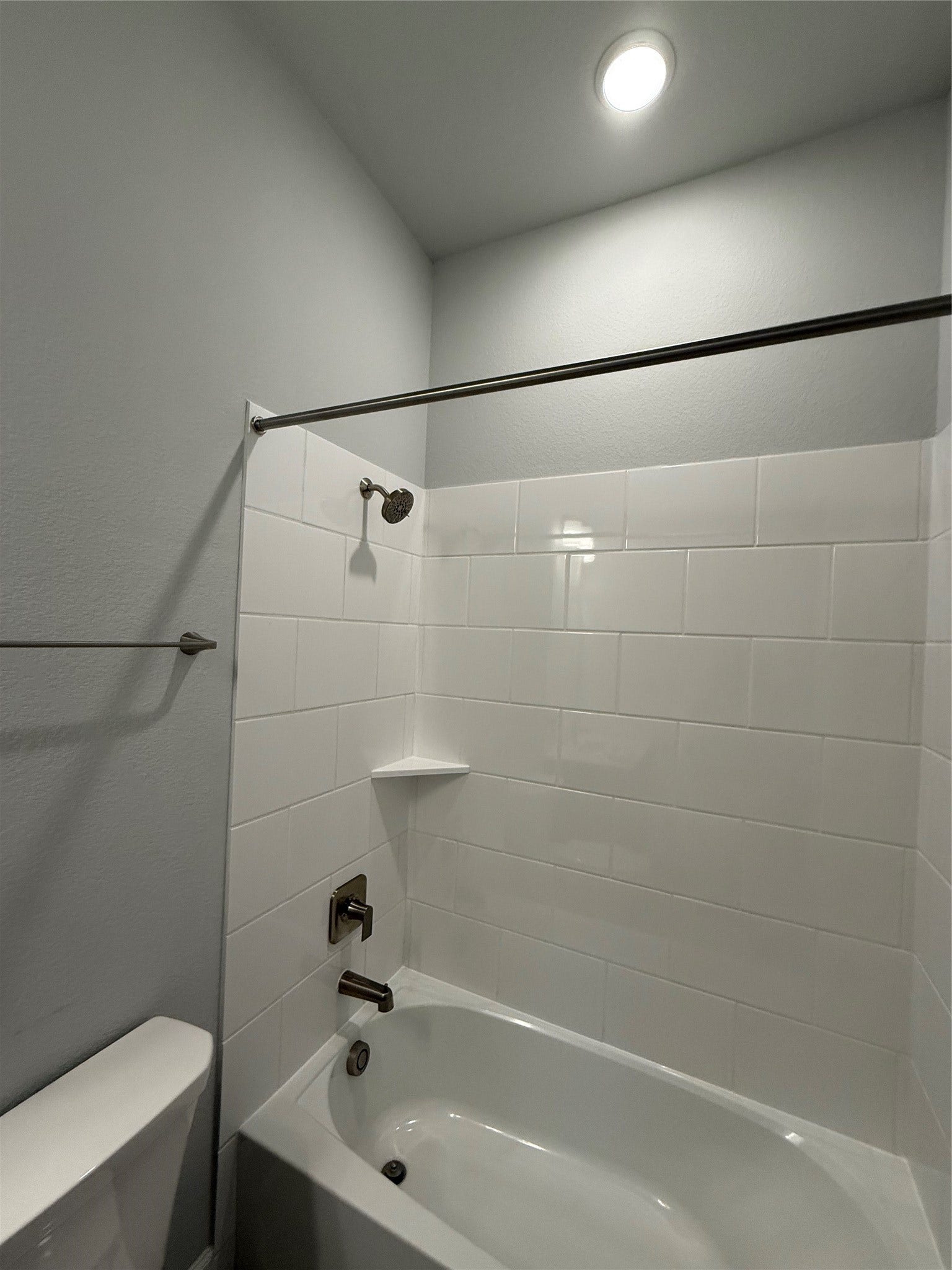 10526 William Park Drive, Missouri City, TX 77459 Modern bathroom featuring a sleek, white-tiled shower and bathtub combination with polished fixtures, creating a fresh and inviting space.