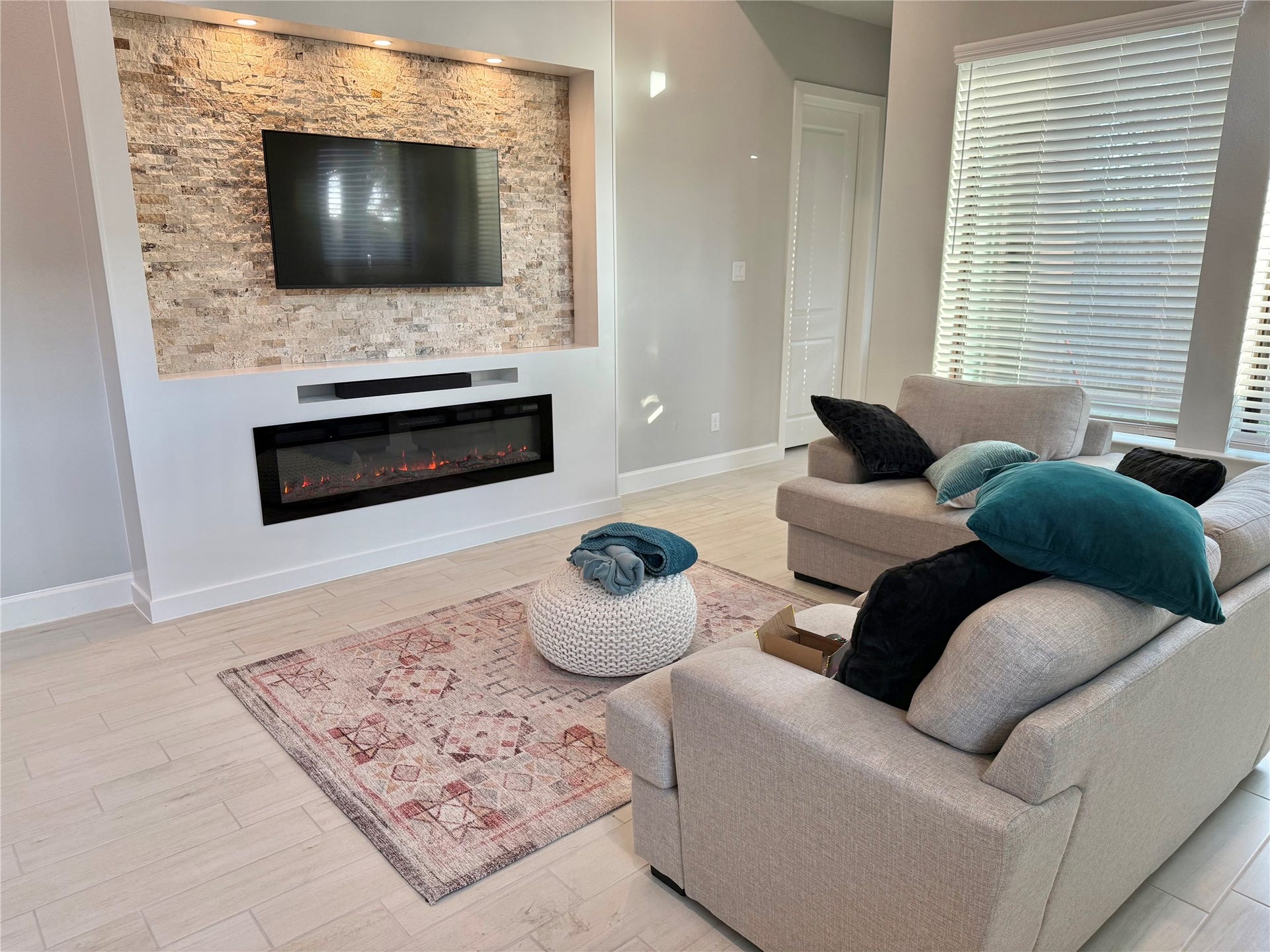 10526 William Park Drive, Missouri City, TX 77459 Cozy living area featuring a modern stone accent wall with a mounted TV and sleek electric fireplace, complemented by plush seating and natural light.
