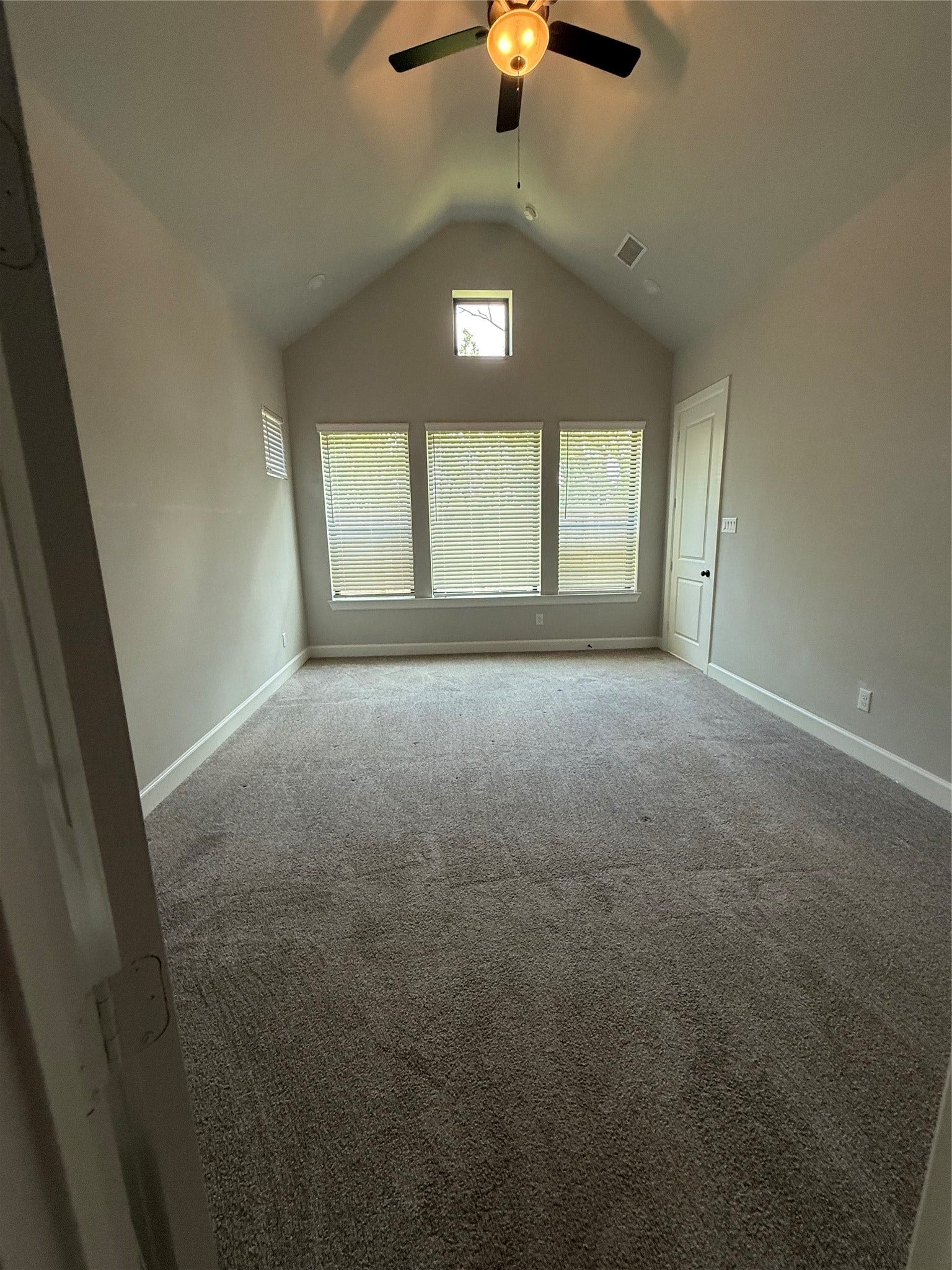 10526 William Park Drive, Missouri City, TX 77459 Spacious bedroom with vaulted ceiling, large windows for natural light, and plush carpeting, creating a cozy yet airy atmosphere.
