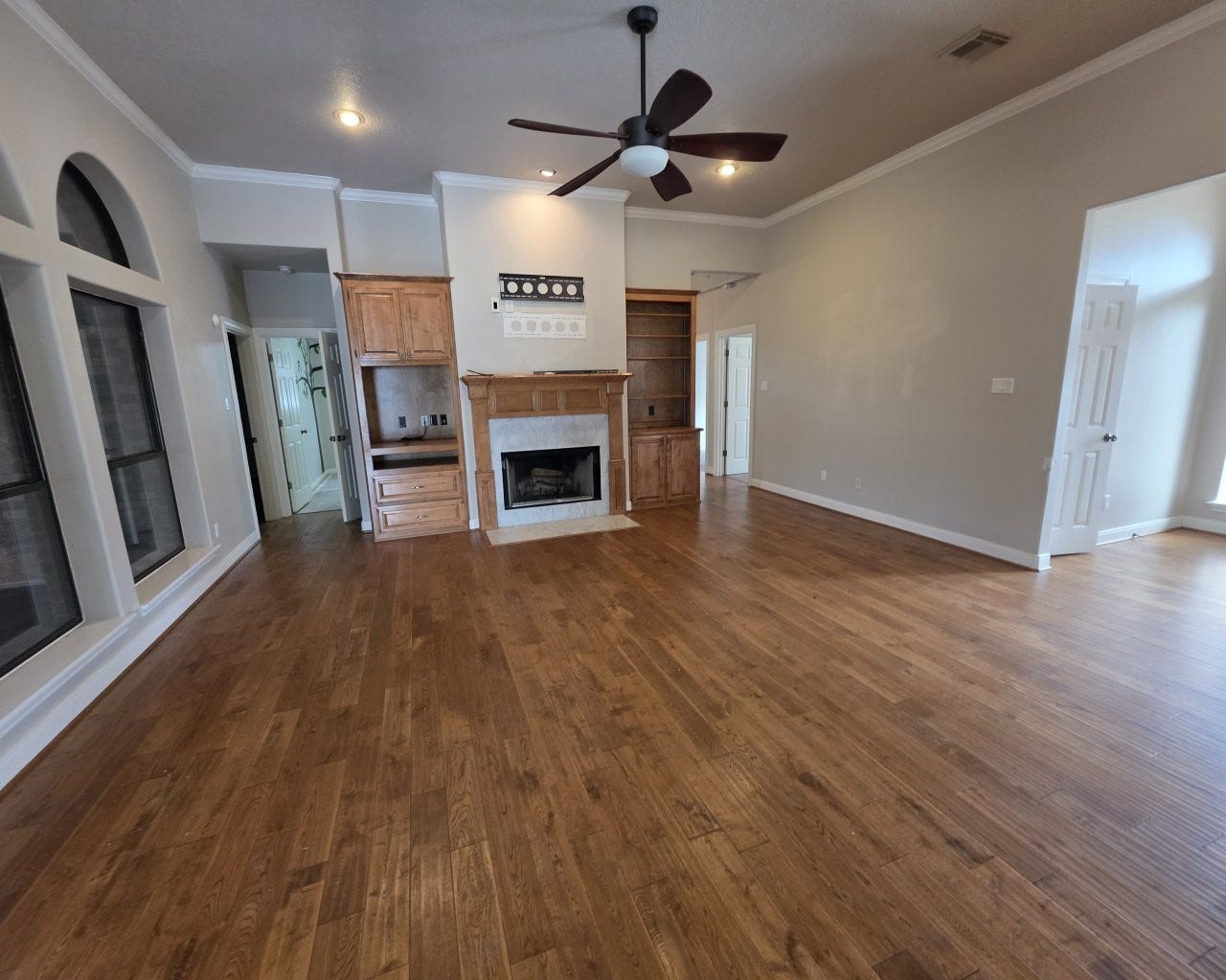 Spacious living area with fireplace, ceiling fans, and built-in cabinets