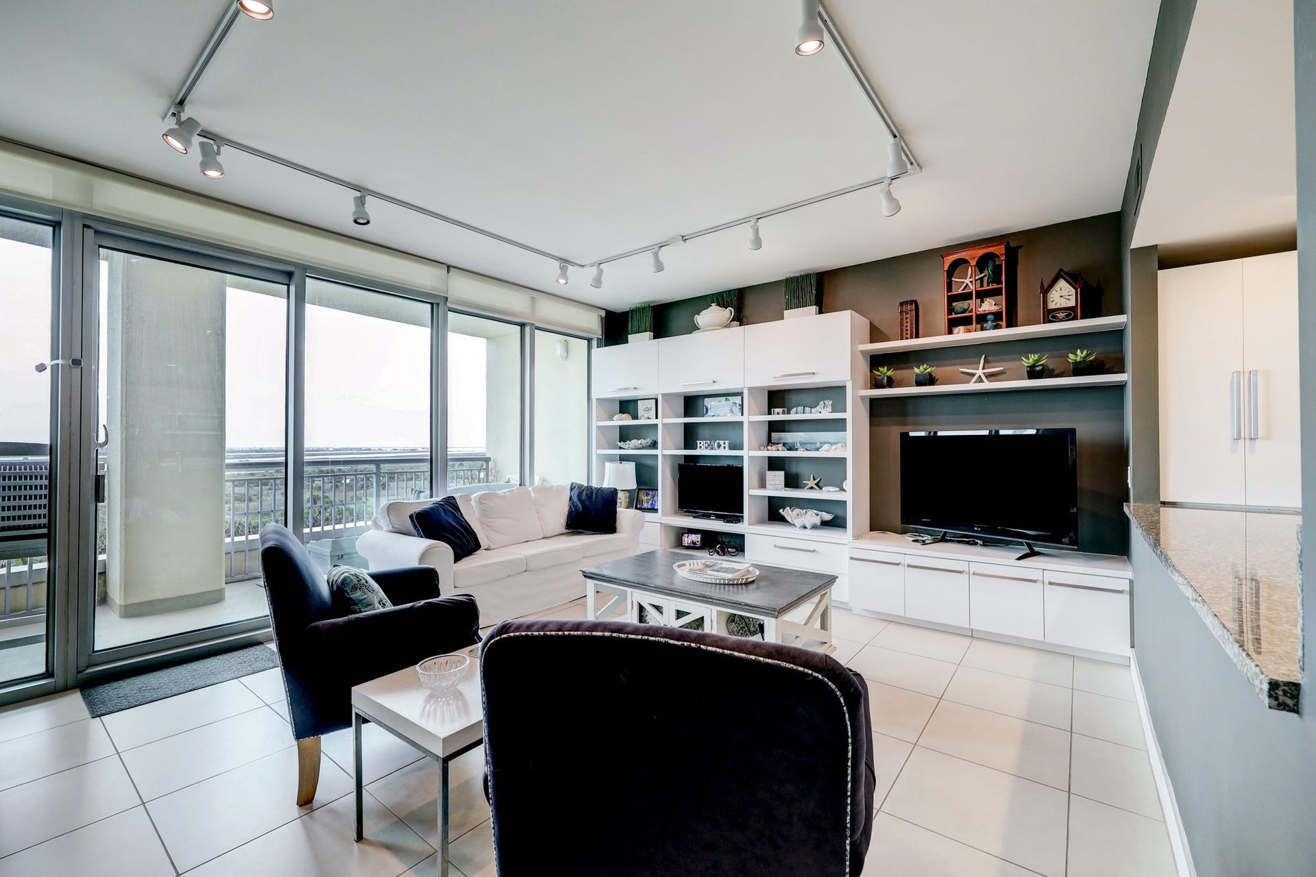 801 E Beach Drive, #BC0412, Galveston, TX 77550 The Living space has floor to ceiling windows and door to let in natural light. It also features a wall of built-ins with loads of storage.