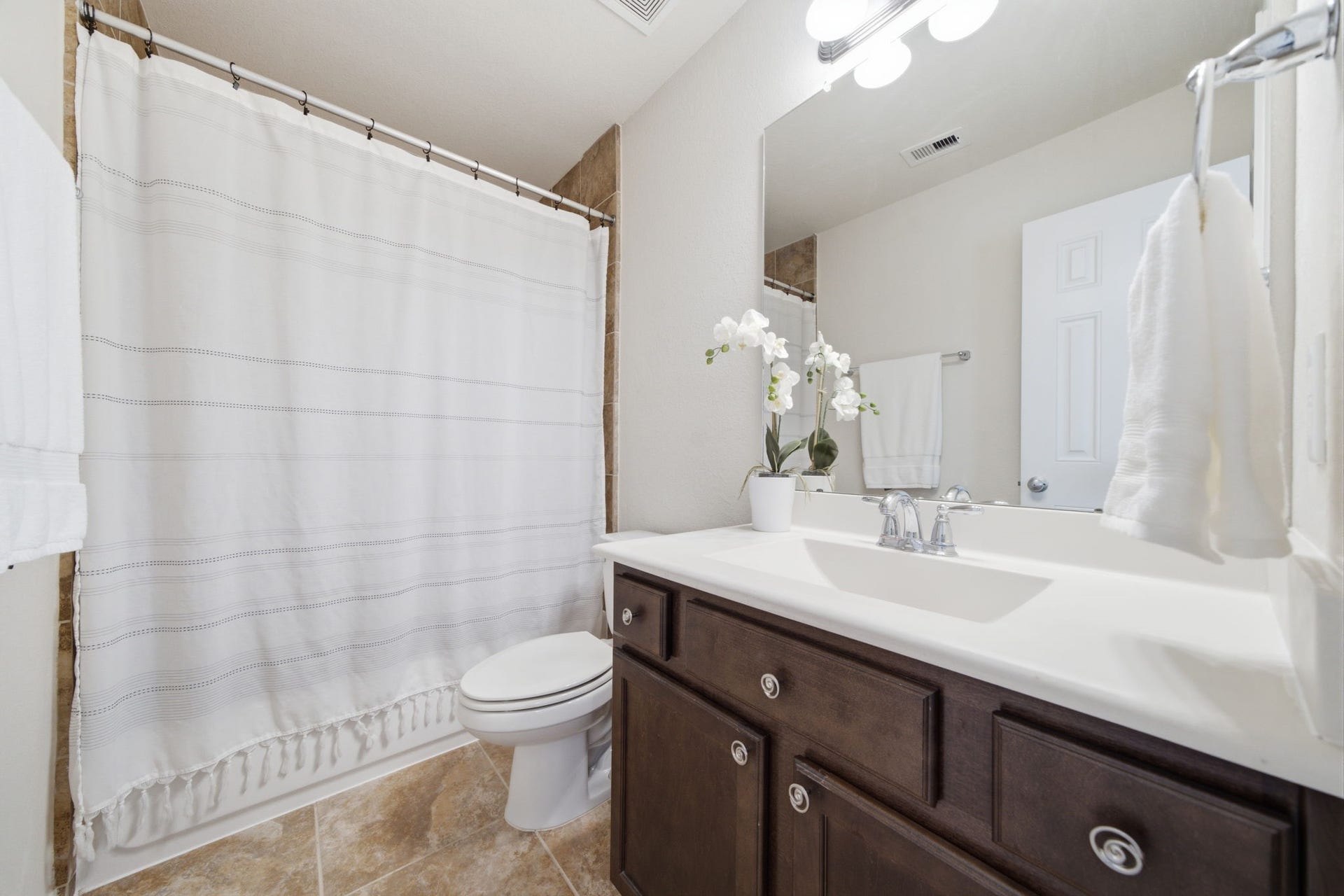 6363 Fairdale Lane, #L, Houston, TX 77057 Full en-suite secondary bathroom features tiled shower & tub combo, maple cabinets w/nickel hardware, chrome fixtures, new mirror, and sturdy white countertop+sink. Clean, simple, and tasteful.