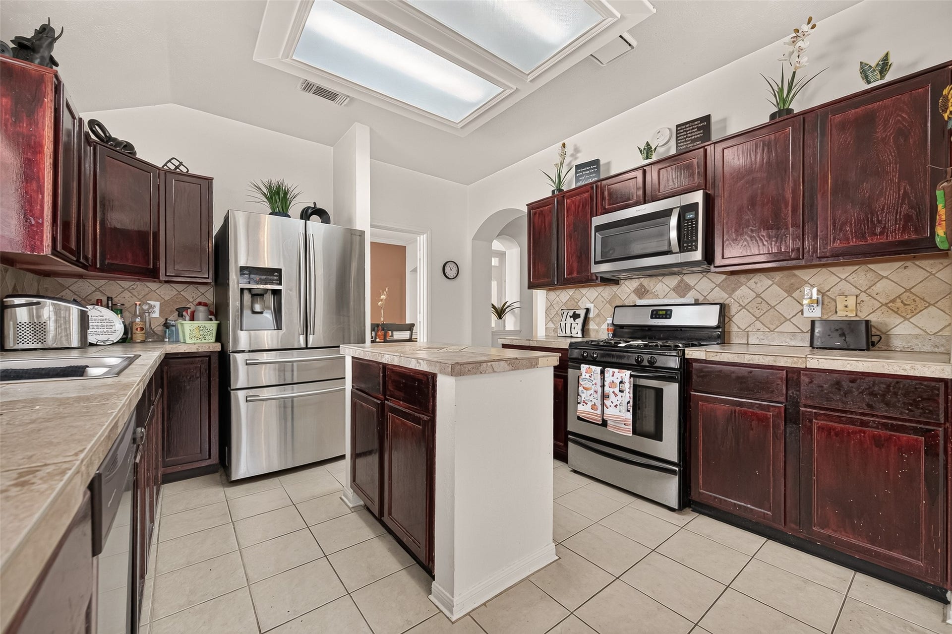 1615 Glacier Blue Drive, Fresno, TX 77545 Charming kitchen with rich dark wood cabinetry, modern stainless steel appliances, and a central island under skylights, offering ample space for culinary creativity.