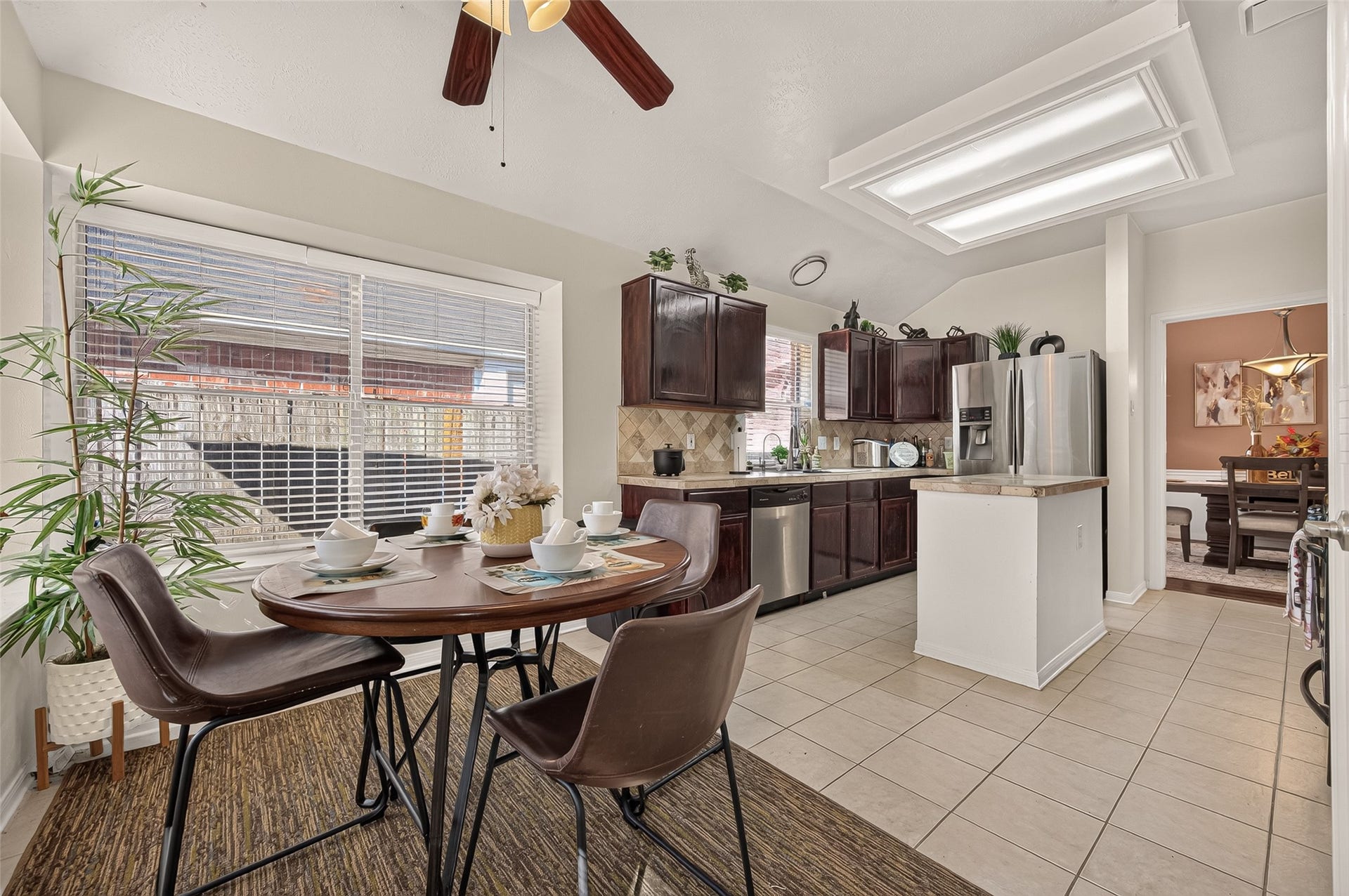 1615 Glacier Blue Drive, Fresno, TX 77545 Bright kitchen with modern stainless steel appliances, dark wood cabinetry, and a cozy breakfast nook by a large window, offering a perfect space for casual dining.