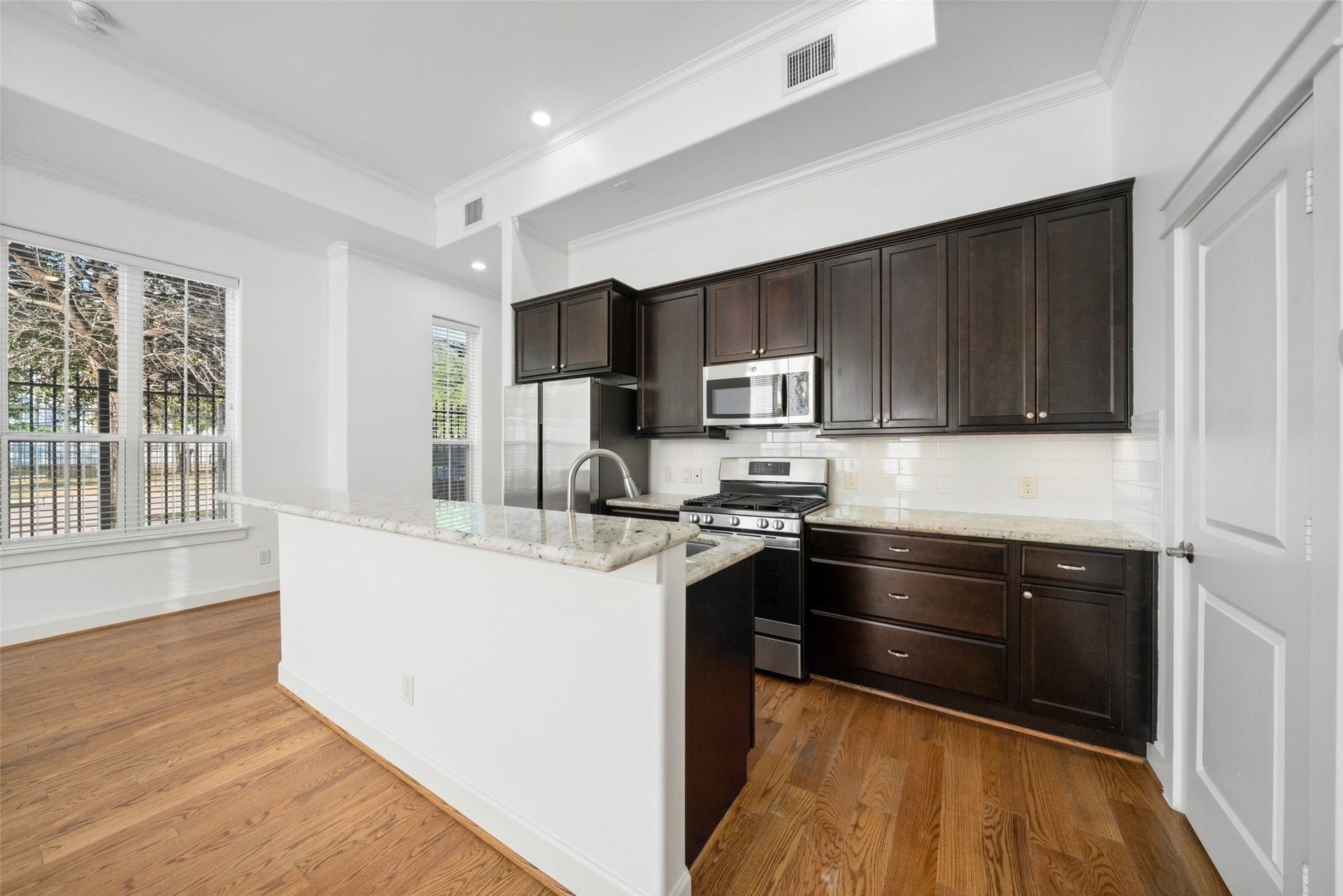 904 W 20th Street, #A, Houston, TX 77008 This kitchen comes equipped with stainless steel appliances, including gas range and a NEW double-door refrigerator, granite countertops, under-cabinet lighting, and an island with a sink and eat-at bar. Your large pantry space and under stairs storage closet is through the door to the right.