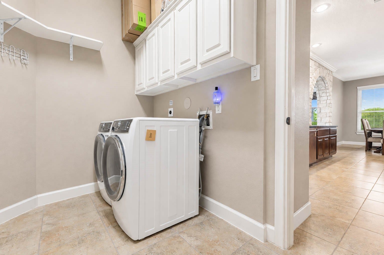 5331 W Farm Way, Fulshear, TX 77441 The utility room, conveniently located off the kitchen, offers ceramic tile flooring, custom cabinetry, washer and dryer connections, and additional shelving.