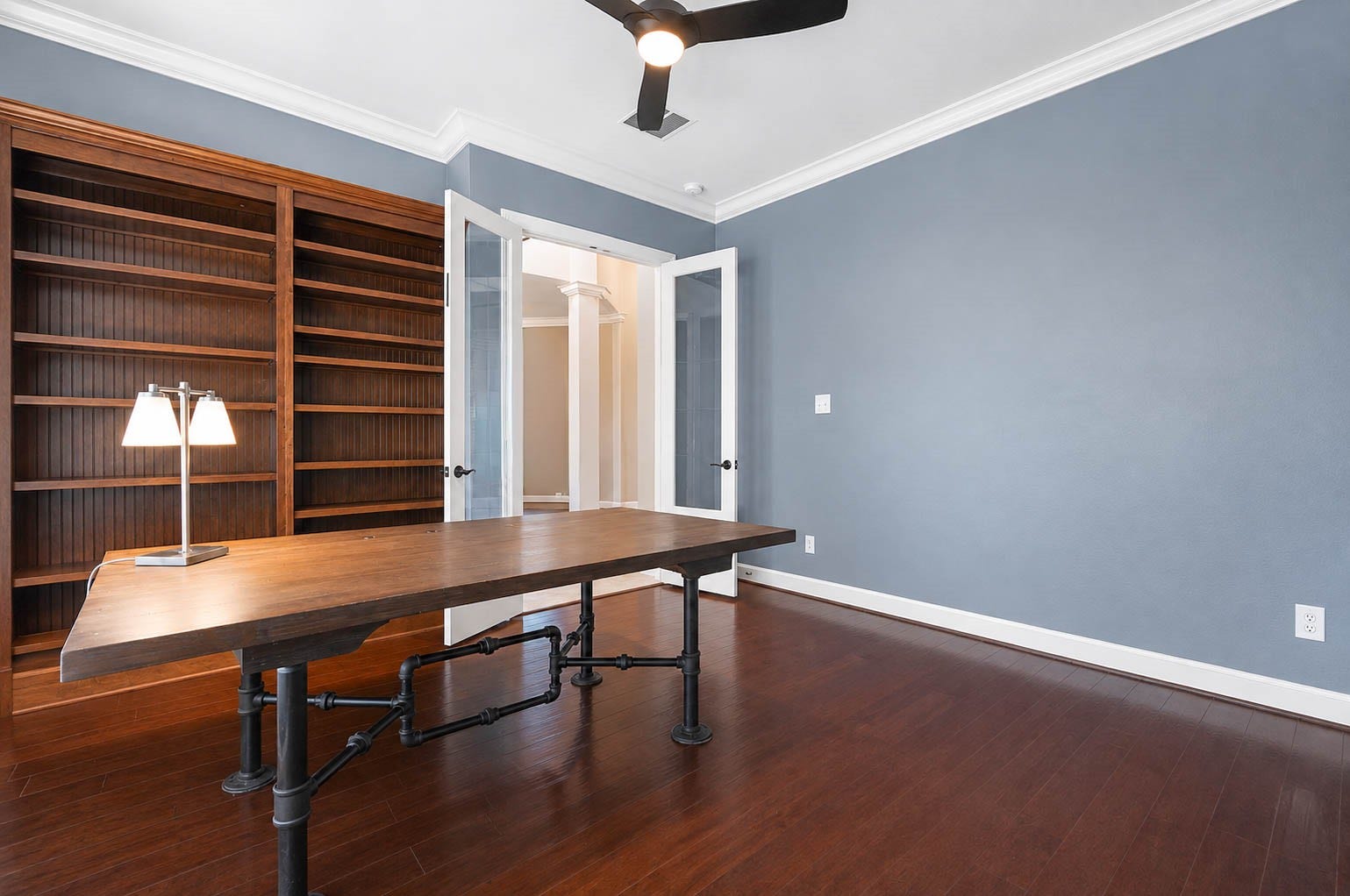5331 W Farm Way, Fulshear, TX 77441 This private study offers hardwood floors, decorator paint, crown molding, and a modern ceiling fan, complemented by custom built in shelving perfect for books or decor.