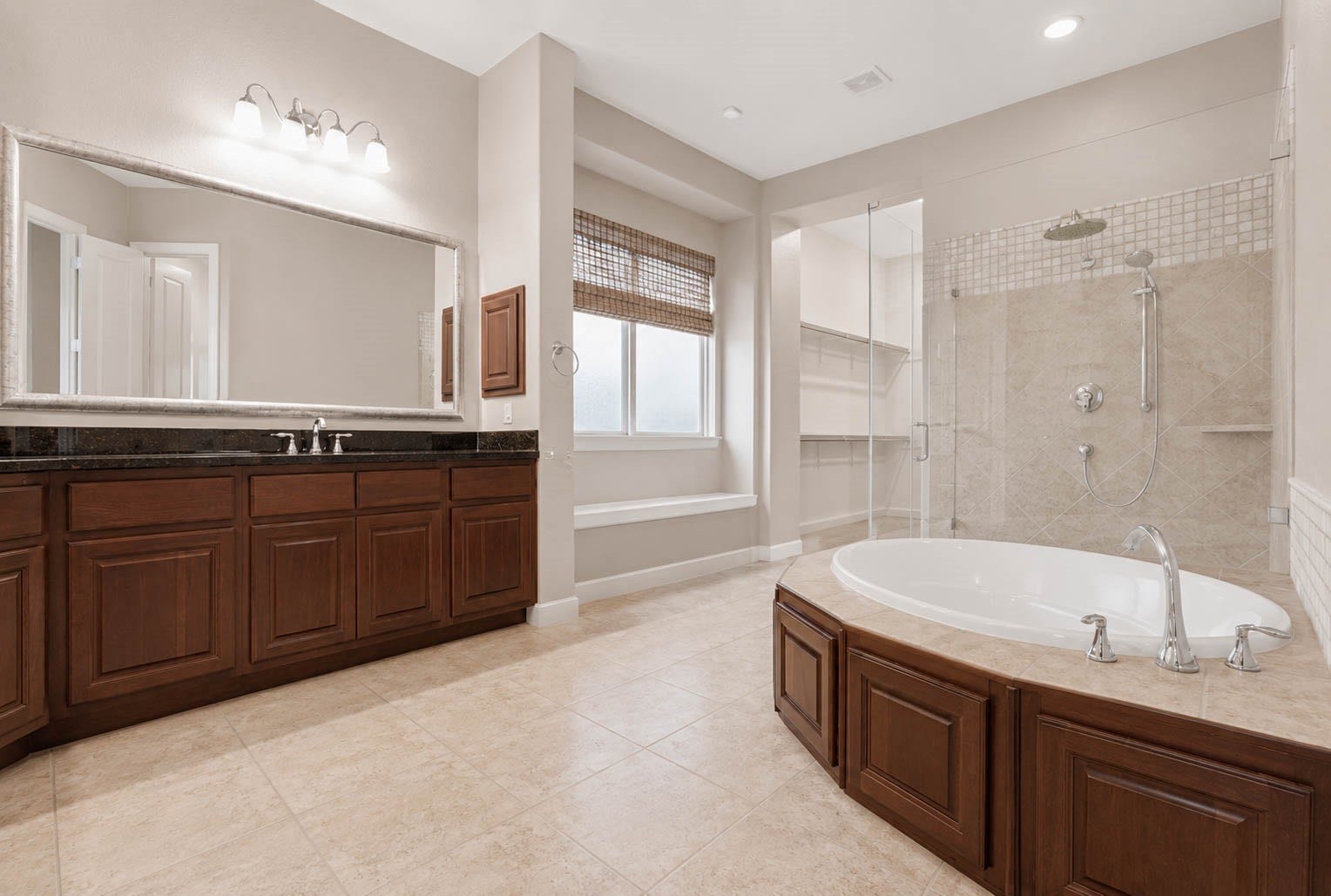 5331 W Farm Way, Fulshear, TX 77441 The primary bathroom offers a large soaking tub, a walk-in tiled shower with rain shower head and wand, and a dual sink vanity with granite countertops, all finished with tile flooring throughout.