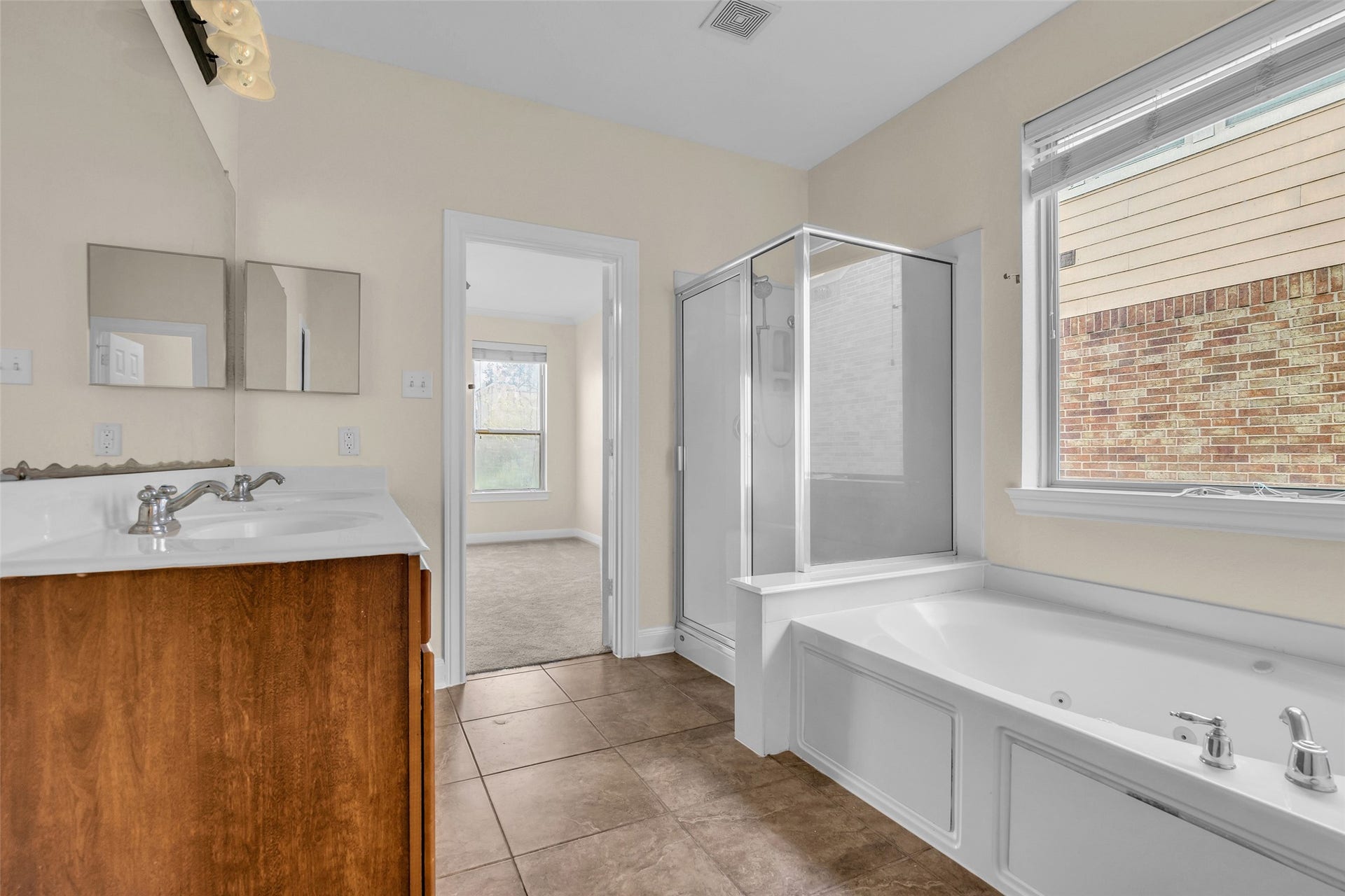 9907 Heritage Waters Court, Humble, TX 77396 The window provides calming natural light. A walk-in shower and relaxing jetted tub finish off the primary bathroom.