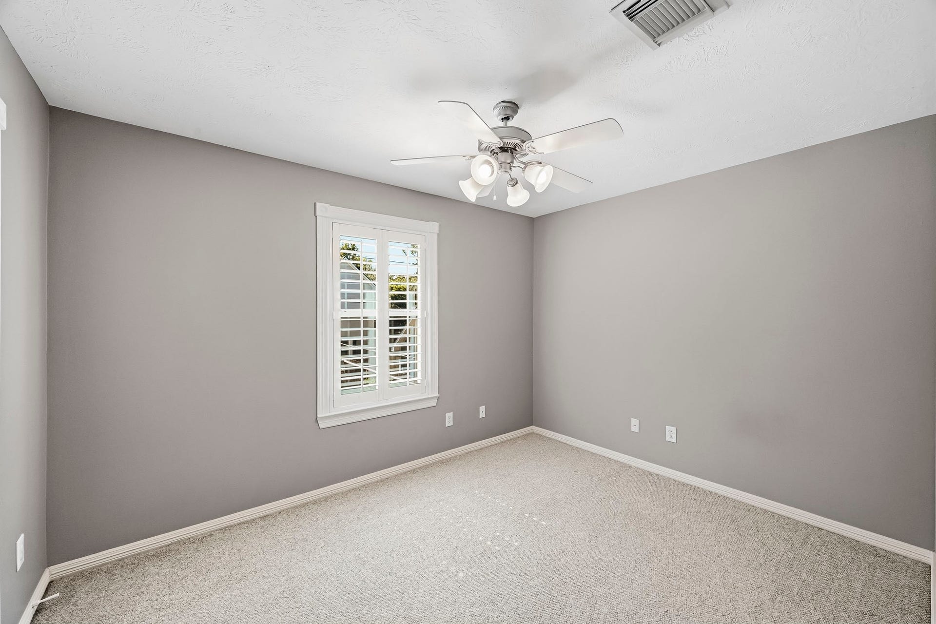 951 Lamonte Lane, Houston, TX 77018 Comfortable secondary bedroom featuring Berber carpet, neutral paint, ceiling fan, and plantation shutters.