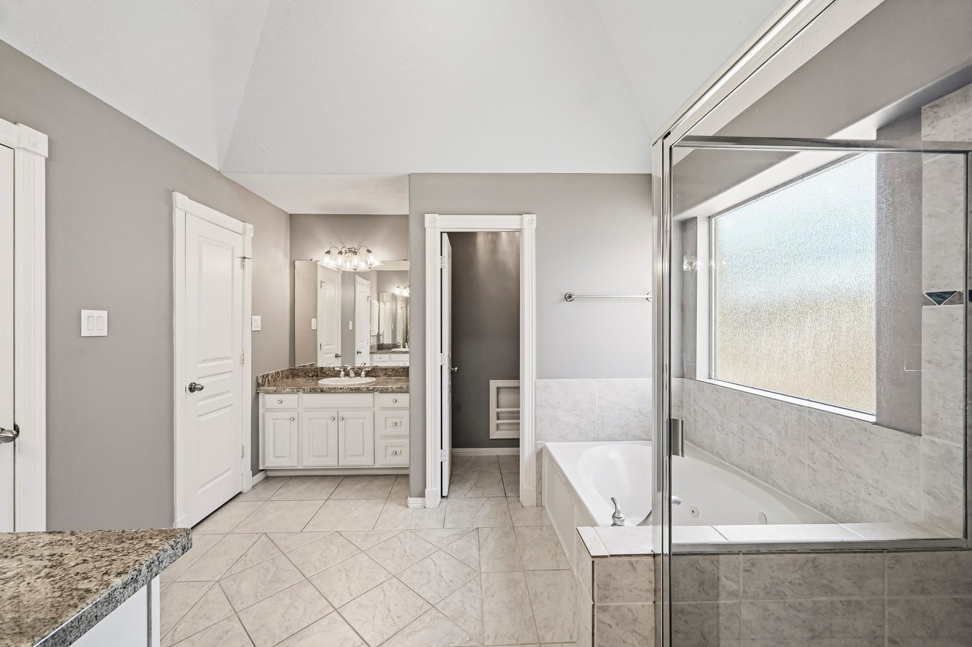 951 Lamonte Lane, Houston, TX 77018 Spacious primary bathroom with granite countertops, tile flooring, a separate soaking tub, and a glass-enclosed shower.