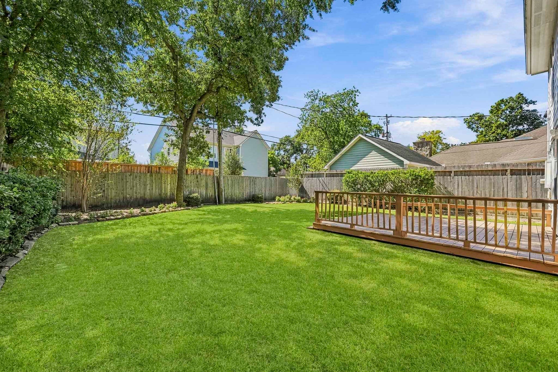951 Lamonte Lane, Houston, TX 77018 Expansive, fully fenced backyard with mature shade trees, lush lawn, and a large wooden deck for outdoor entertaining.