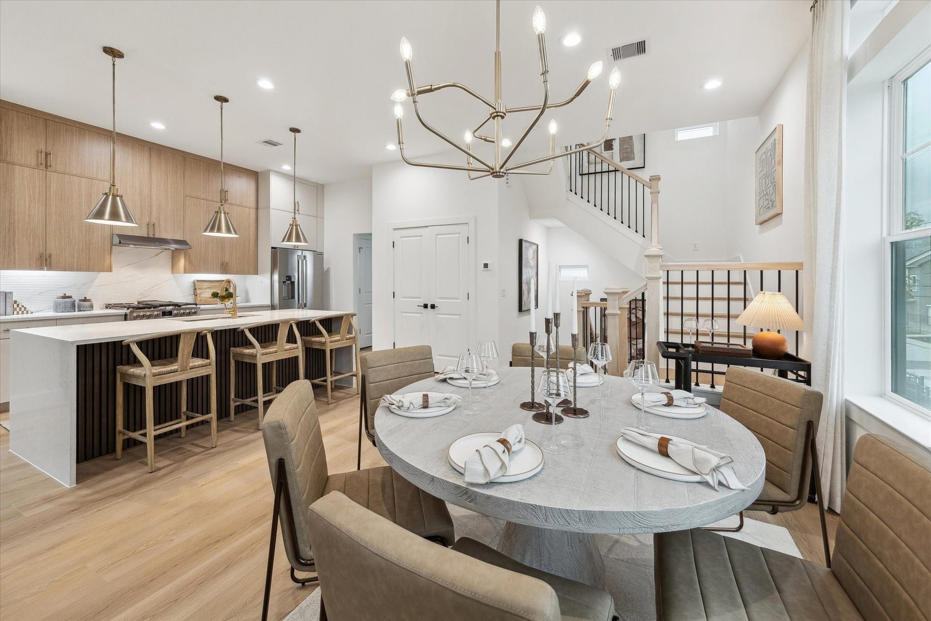 Elegant open-concept dining and kitchen area featuring a modern chandelier, sleek cabinetry, and a spacious island with seating. Perfect for entertaining and family gatherings.