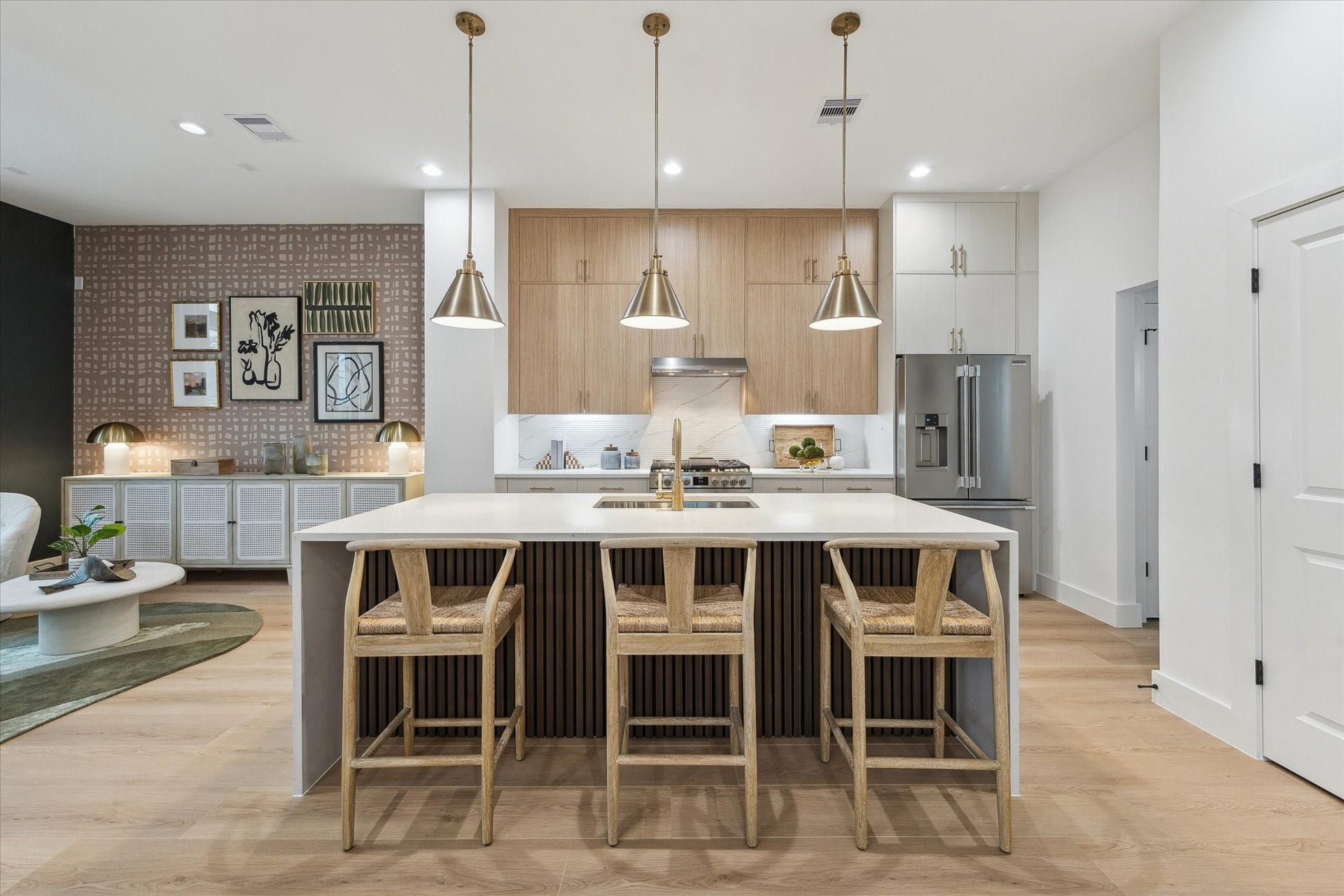 Sleek and modern kitchen featuring a spacious island with seating for four, stylish pendant lighting, and stainless steel appliances.