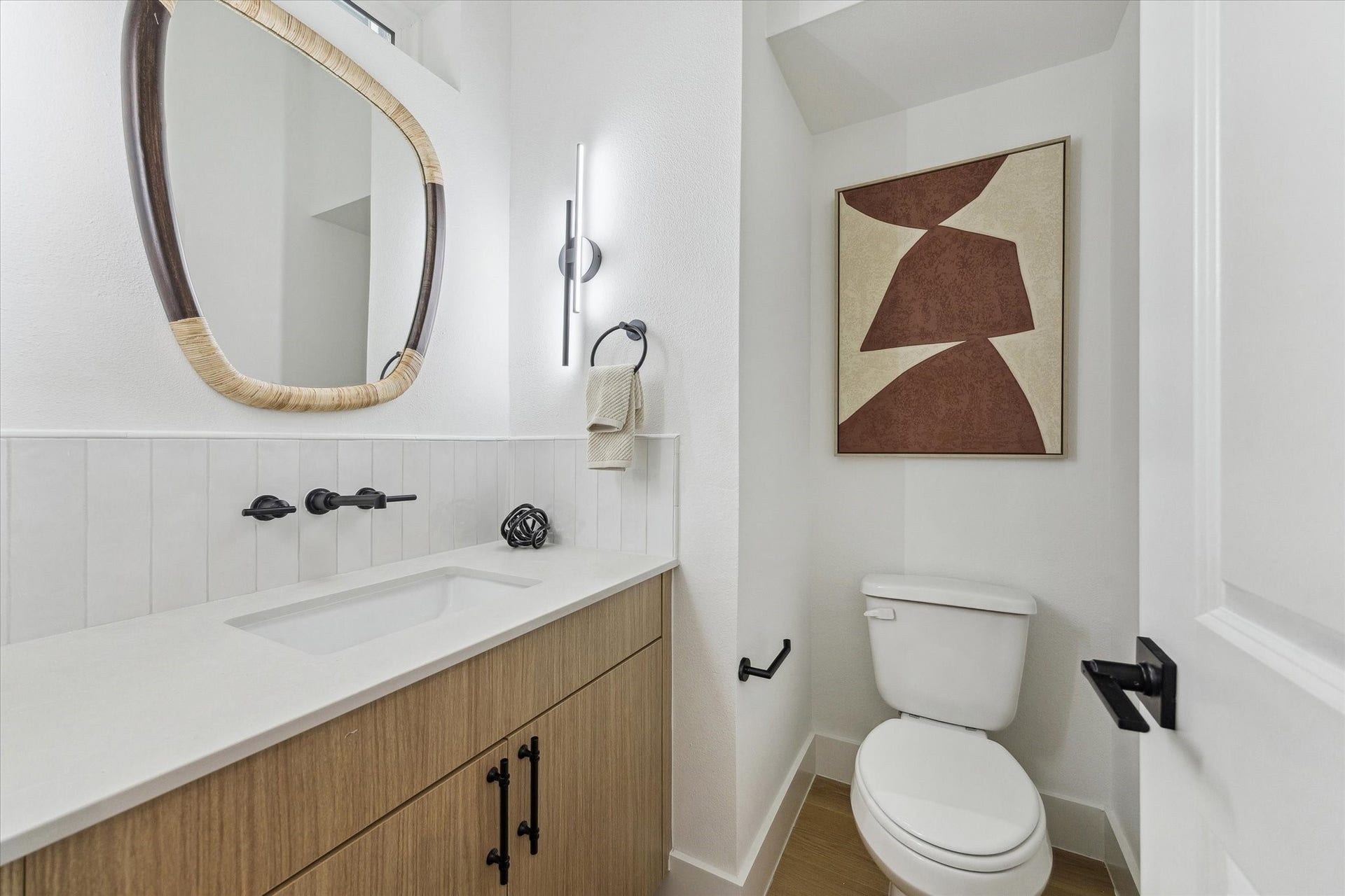 Modern bathroom featuring a sleek vanity with a stylish mirror, contemporary fixtures, and eye-catching wall art.