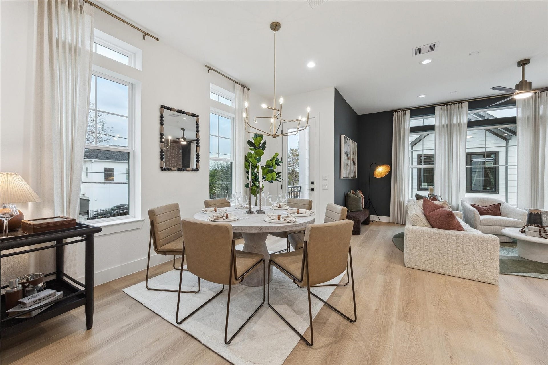 Elegant open-concept living and dining area featuring a modern chandelier, large windows for natural light, and stylish furnishings for a warm, inviting atmosphere.