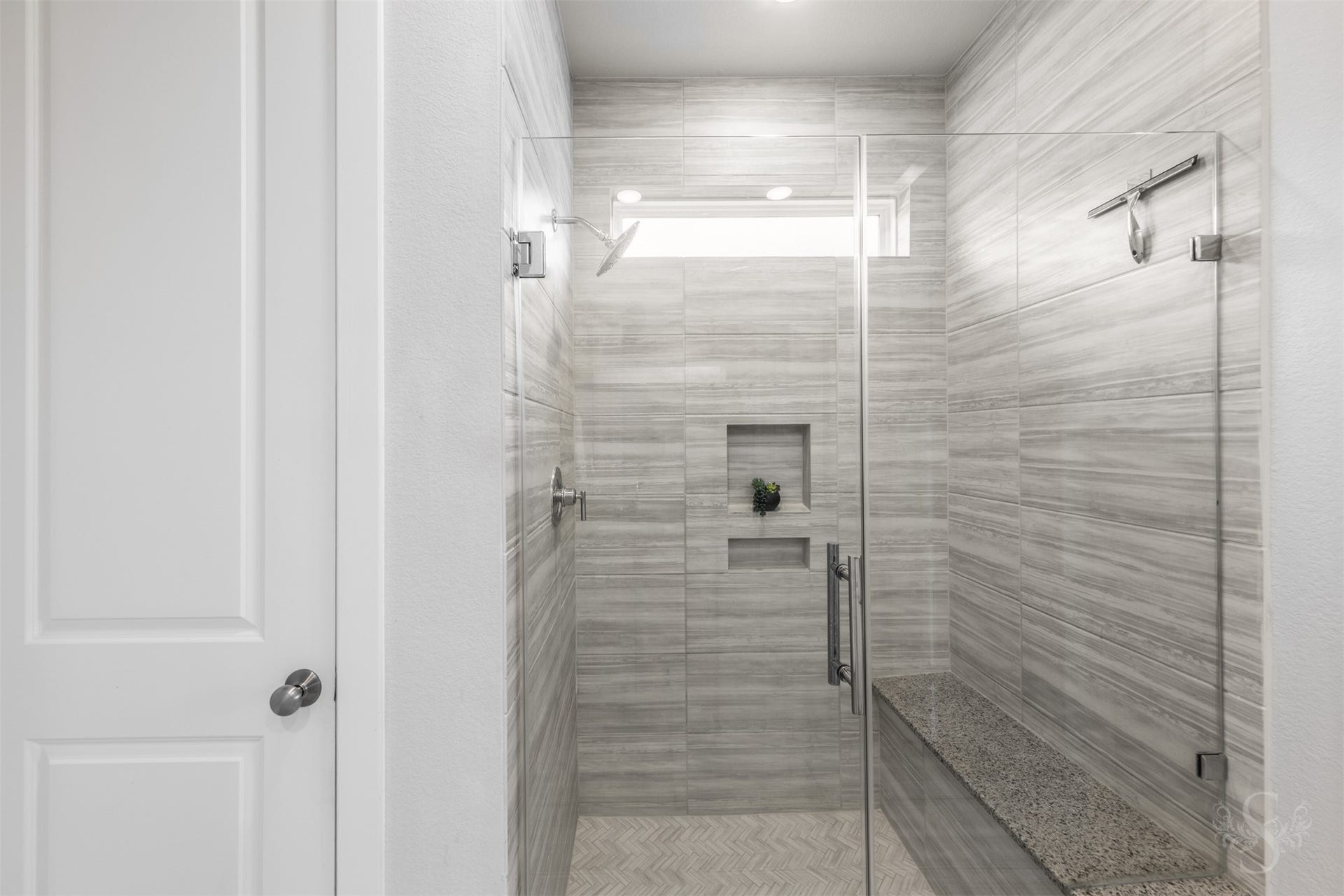 20922 Maudine Drive, Cypress, TX 77433 The luxurious walk-in shower showcases a frameless glass enclosure, beautiful tilework and a built-in bench. Recessed niches provide convenient storage, while a high window welcomes daylight into this relaxing space.