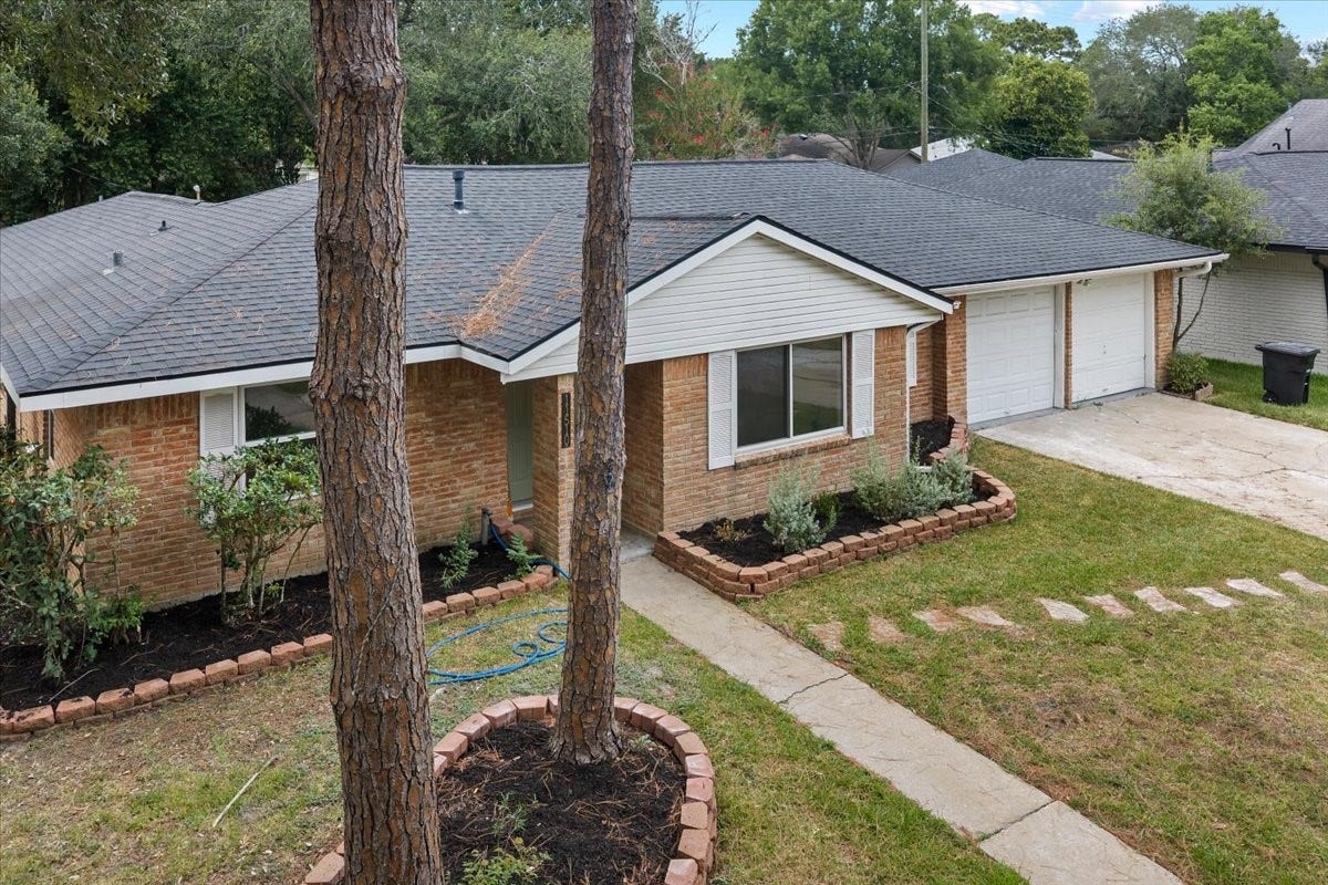 11510 Mullins Drive, Houston, TX 77035 Charming brick home with a spacious two-car garage, surrounded by lush greenery and a well-maintained garden.