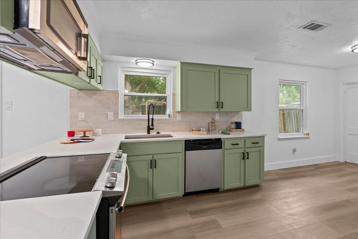 11510 Mullins Drive, Houston, TX 77035 A bright and inviting kitchen featuring sleek green cabinets, modern appliances, and ample counter space for culinary creativity.