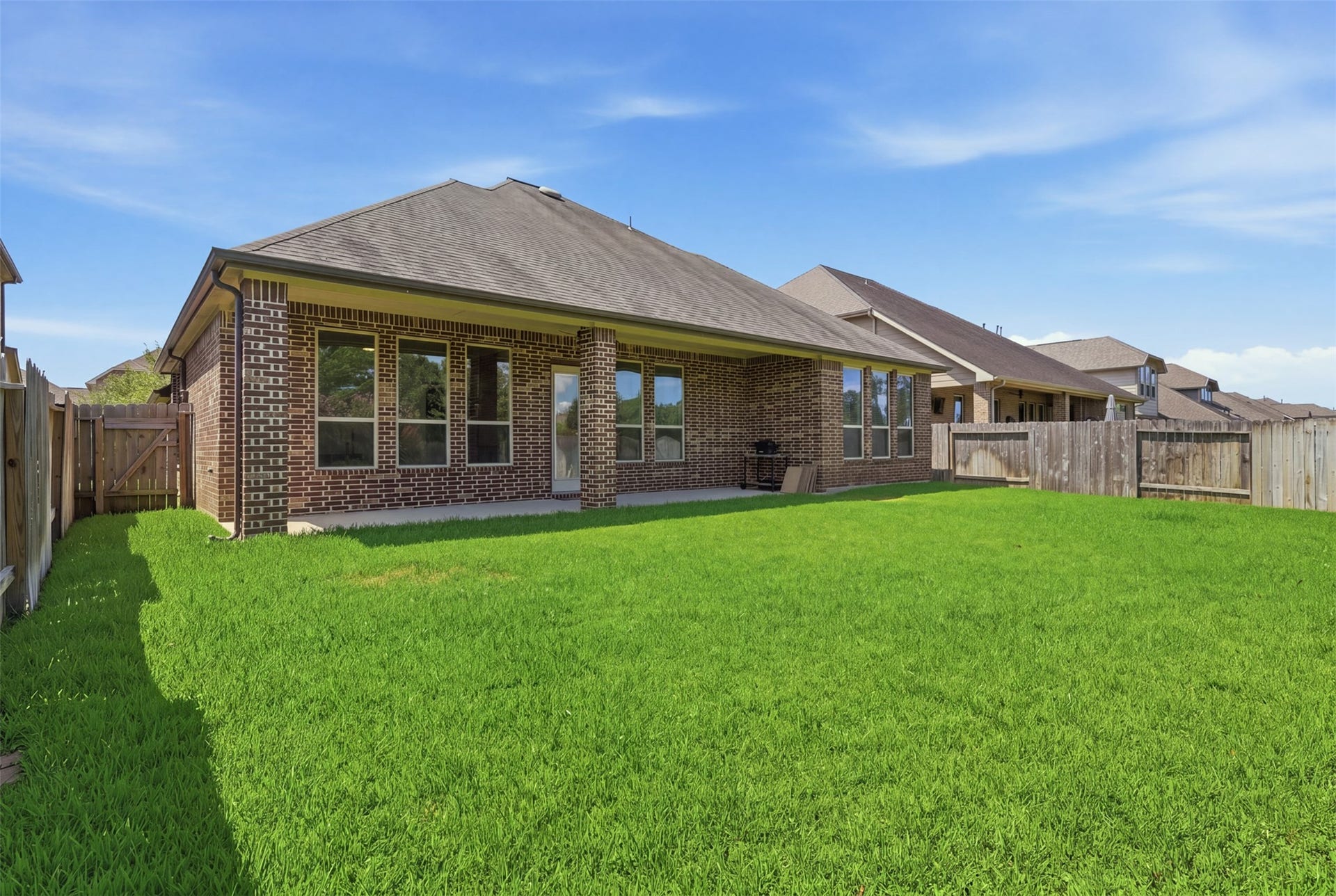 Rear exterior view highlights the spacious yard and covered patio.