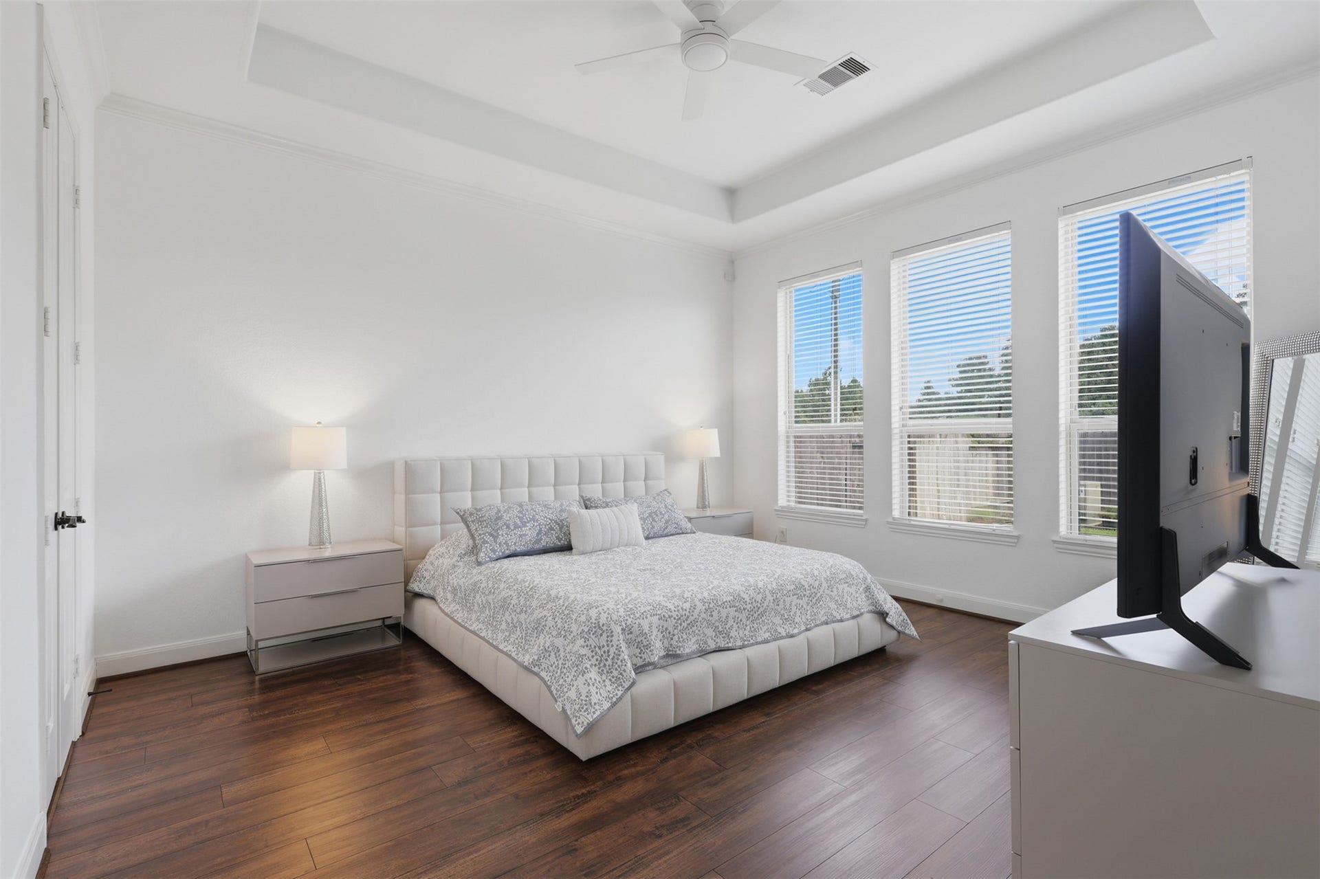 Spacious primary bedroom with wood vinyl flooring and abundant natural light.