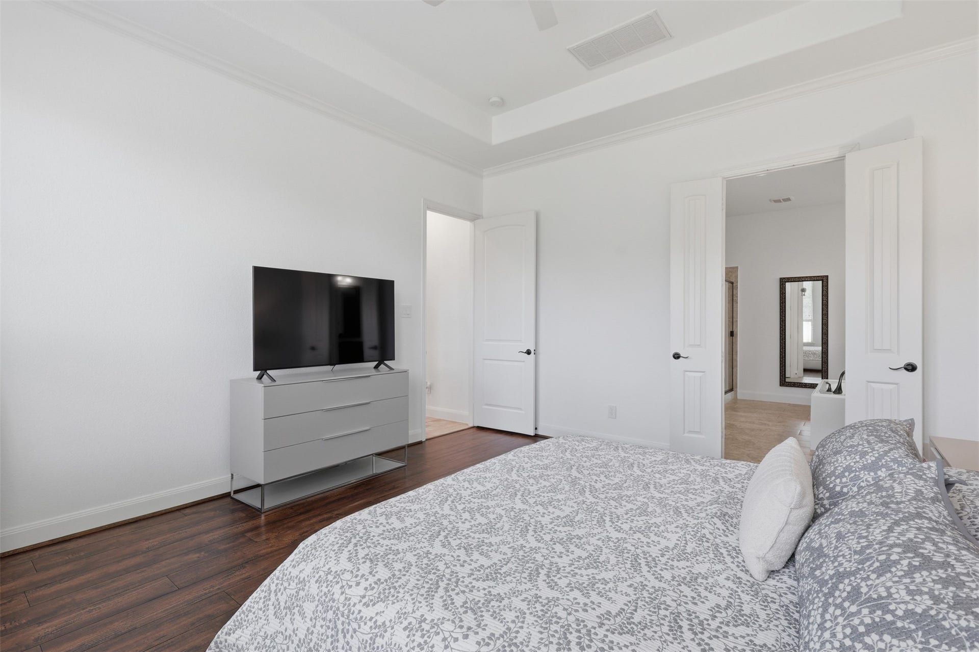 Additional view of the primary suite with tray ceiling and plenty of room for a sitting area.