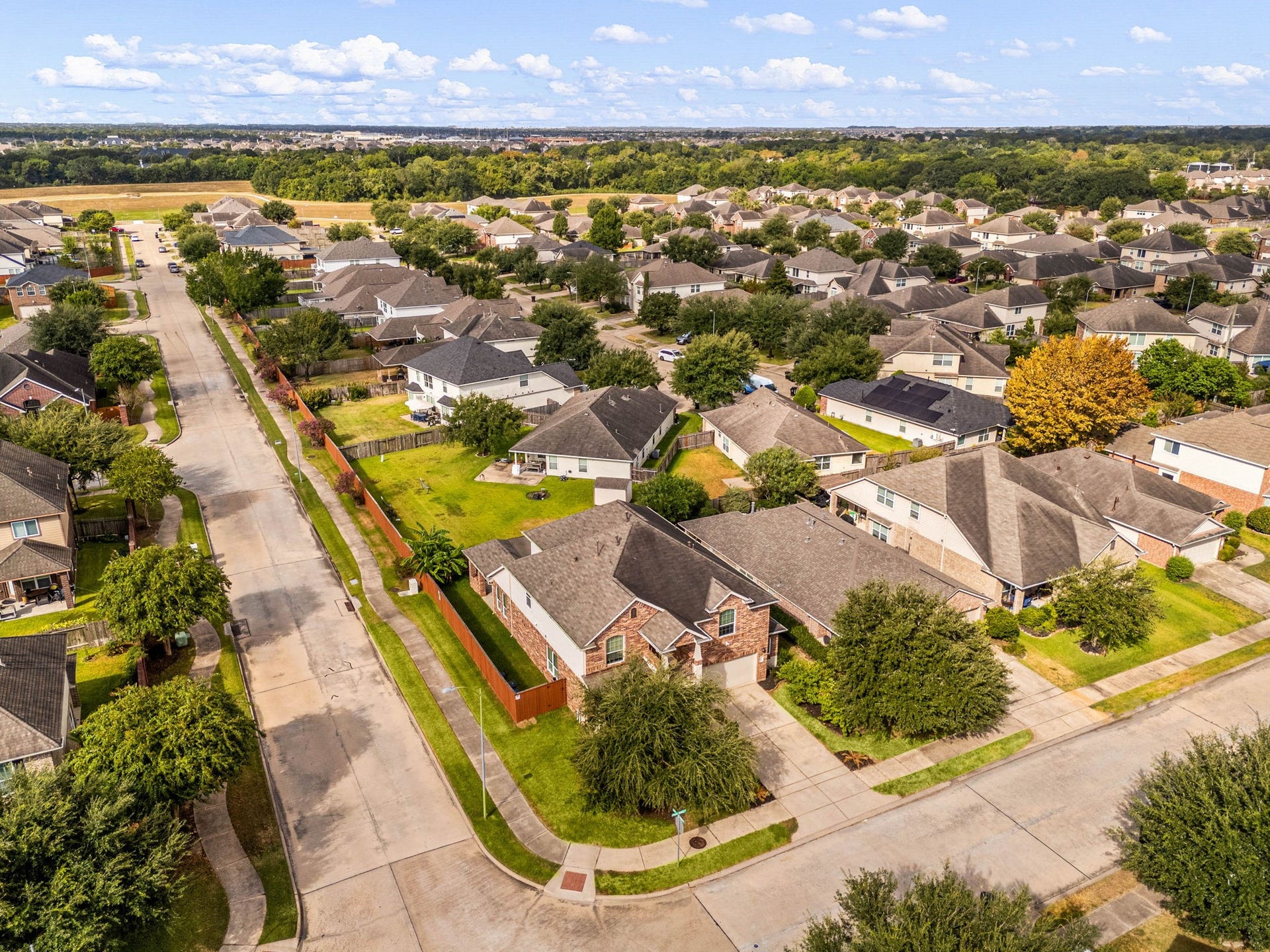 This premier corner-lot home offers great curb appeal, enhanced privacy, and a beautifully manicured perimeter. This stunning neighborhood view highlights the home's prominent corner placement, a private fenced backyard, and a wide-stretching side lawn that separates you from the quiet street, making it one of the most desirable lots in the entire community.