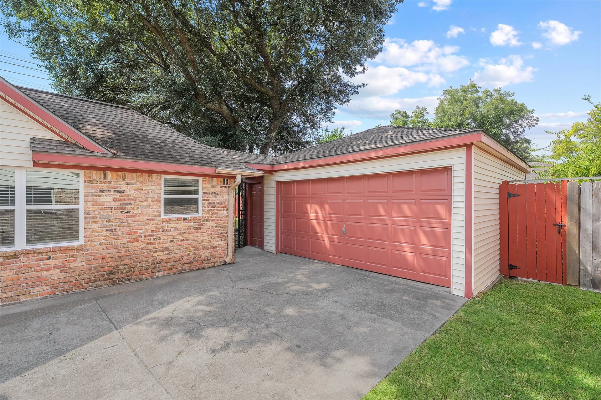2503 Moss Hill Drive, Houston, TX 77080 Charming home with a two-car garage featuring a distinctive red door, complemented by a brick and siding exterior. The property offers a spacious driveway and a private fenced yard, perfect for enjoying outdoor activities.
