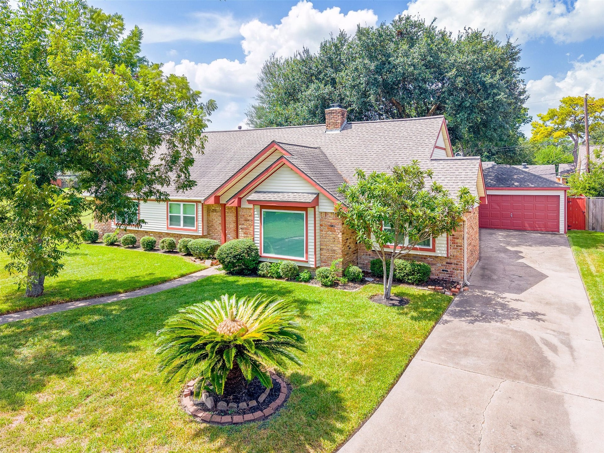 2503 Moss Hill Drive, Houston, TX 77080 Charming brick home with manicured landscaping, featuring a lush lawn and mature trees. A welcoming driveway leads to a detached garage, adding to the property's curb appeal.