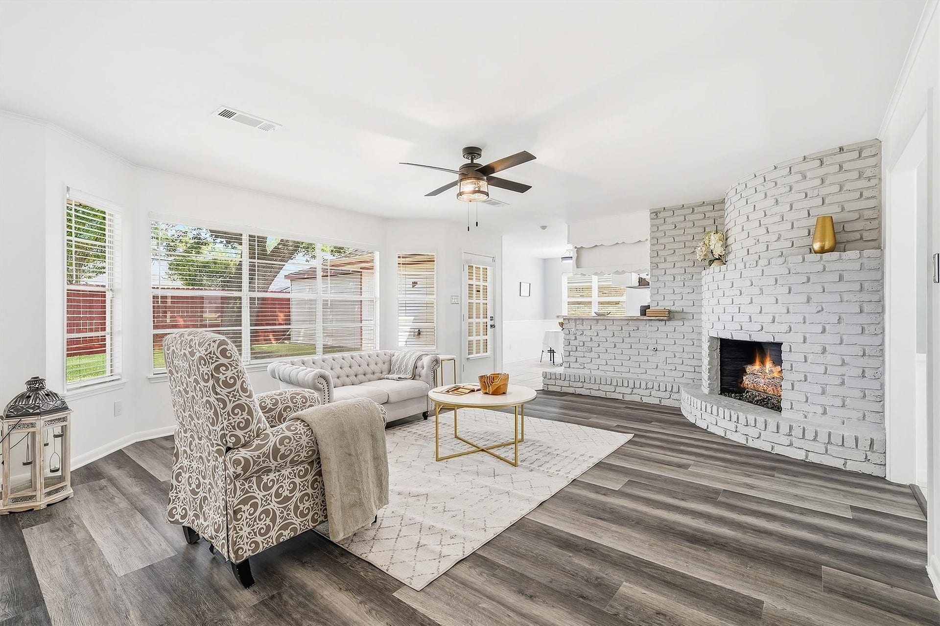 2503 Moss Hill Drive, Houston, TX 77080 Bright and inviting living room featuring stylish vinyl plank flooring, a cozy fireplace with white brick surround, and ample natural light from large windows.