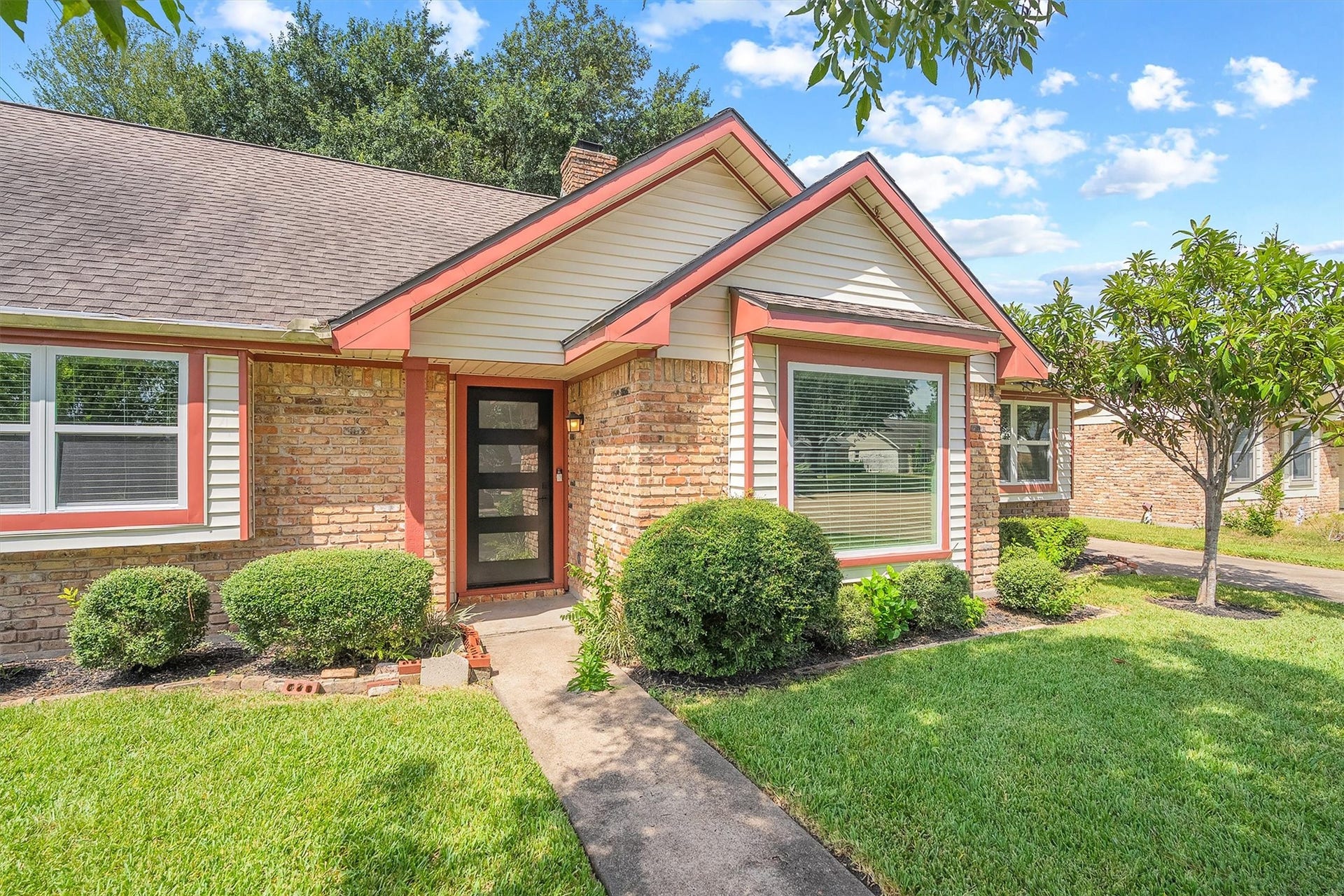 2503 Moss Hill Drive, Houston, TX 77080 Charming brick home with a modern front door, well-maintained landscaping, and a welcoming pathway surrounded by lush greenery.