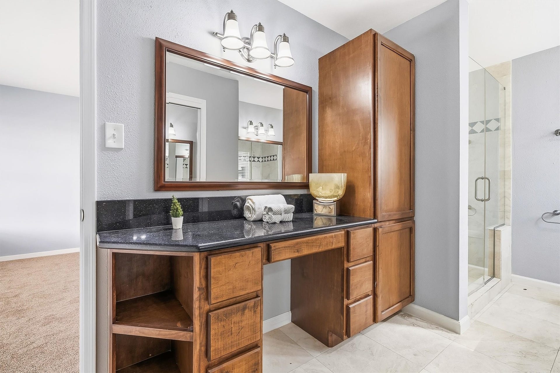 2503 Moss Hill Drive, Houston, TX 77080 Elegant primary bathroom featuring a sleek vanity with rich wood cabinetry, a large mirror, and modern lighting, complemented by a glass-enclosed shower for a touch of luxury.