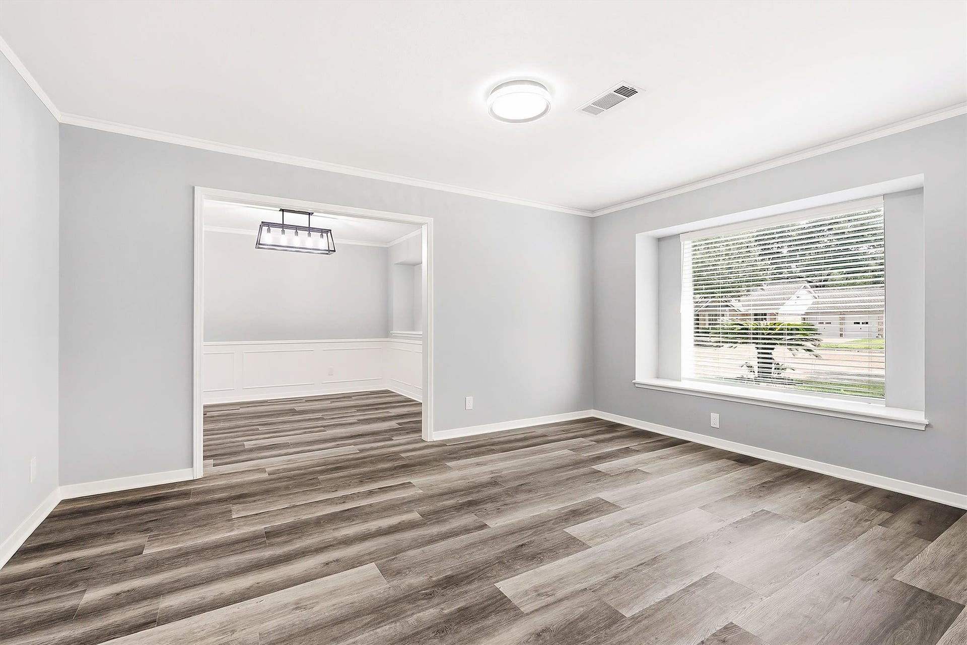 2503 Moss Hill Drive, Houston, TX 77080 Bright and spacious second living area with modern vinyl plank flooring, large window, and an open layout leading to a dining space with stylish lighting.