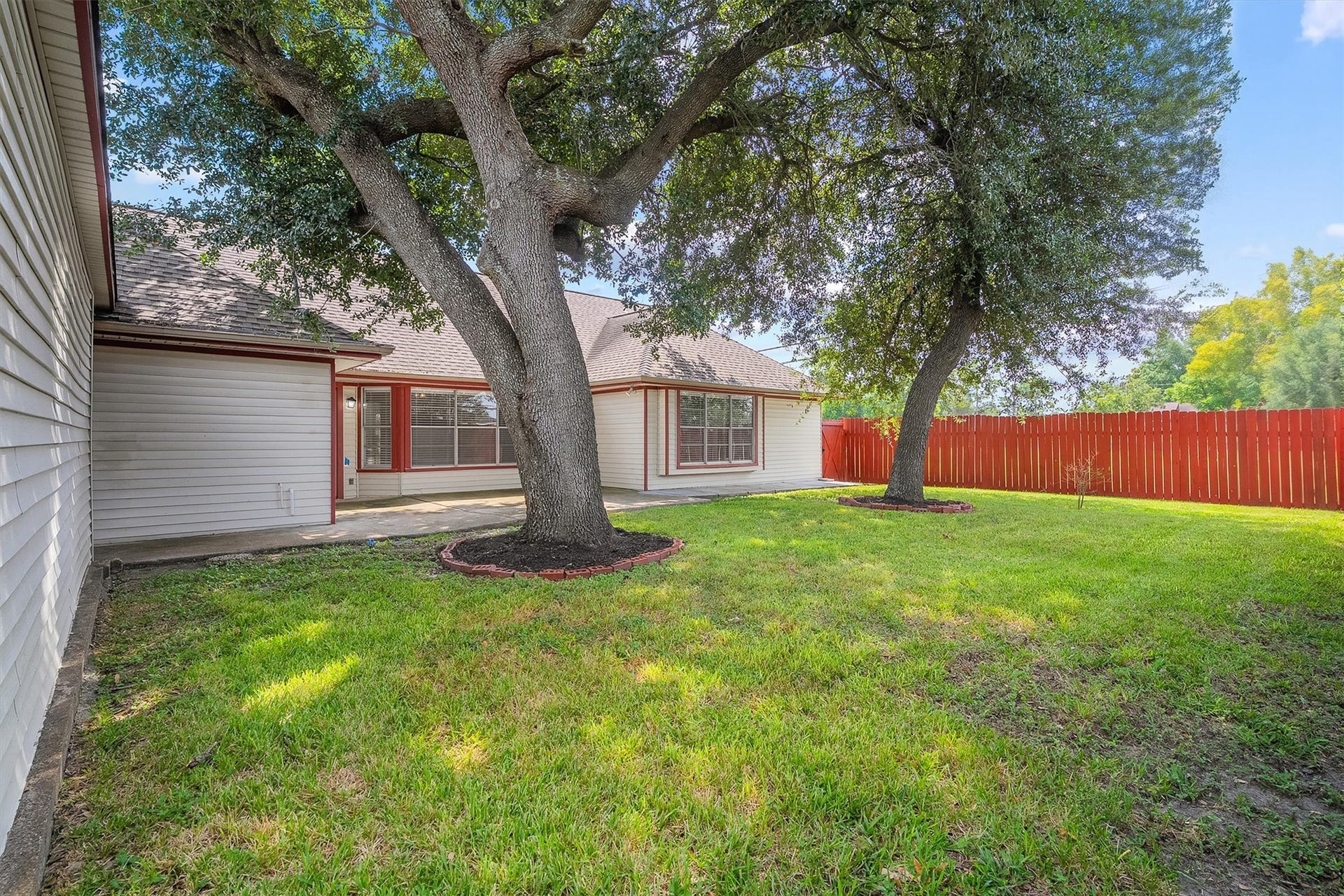 2503 Moss Hill Drive, Houston, TX 77080 Charming home with a two-car garage featuring a distinctive red door, complemented by a brick and siding exterior. The property offers a spacious driveway and a private fenced yard, perfect for enjoying outdoor activities.