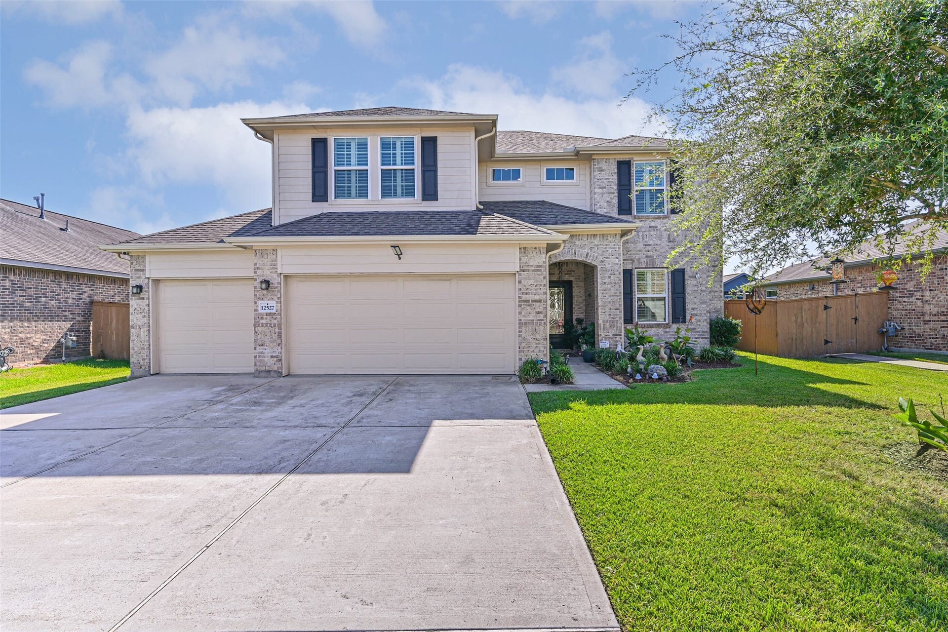 12527 Jetty Cove Drive, Texas City, TX 77568 Welcoming front elevation showcasing the home's spacious driveway, landscaped lawn, and three-car garage.