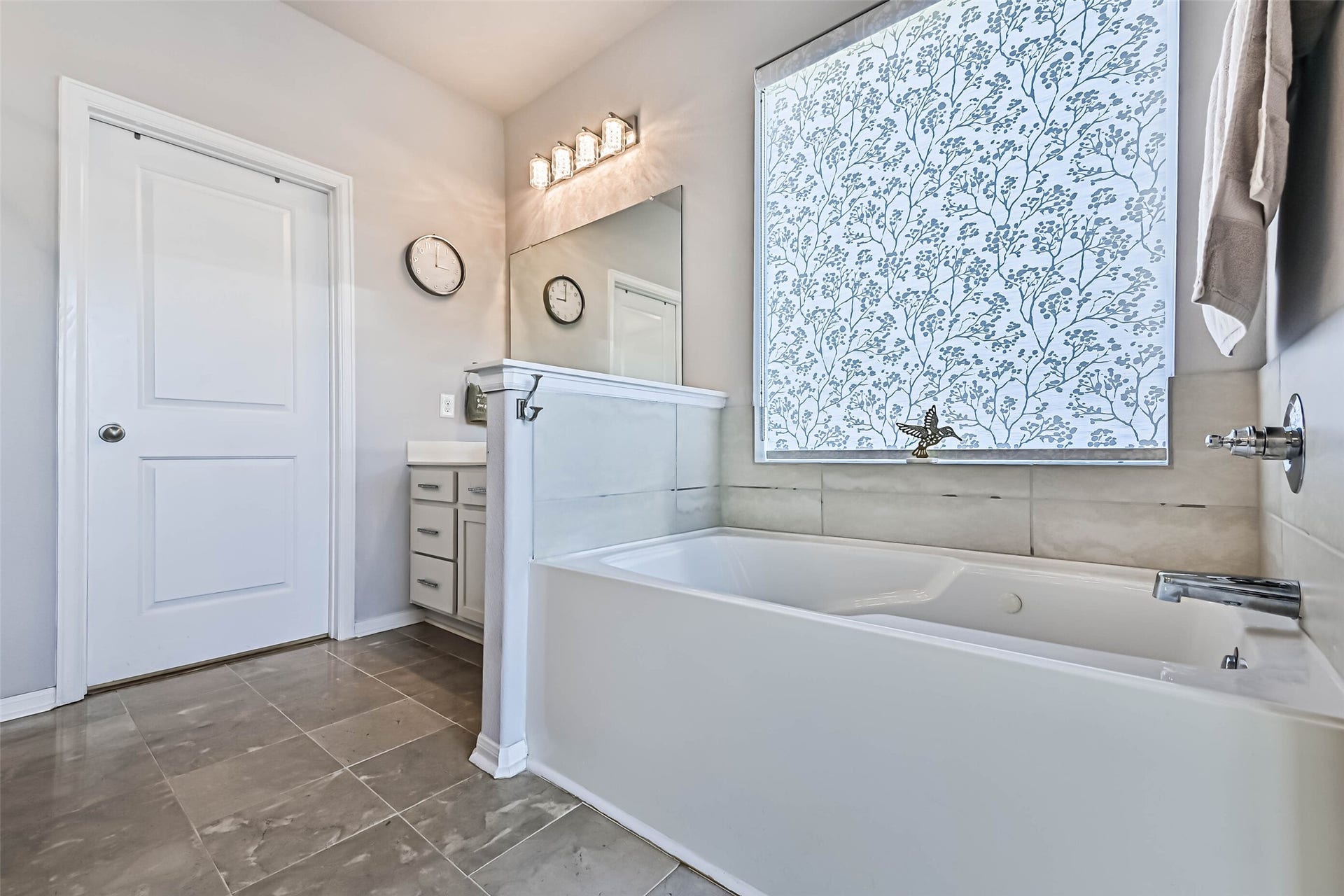 12527 Jetty Cove Drive, Texas City, TX 77568 Relaxing soaking tub with tile surround, natural light, and a decorative window shade for added privacy.