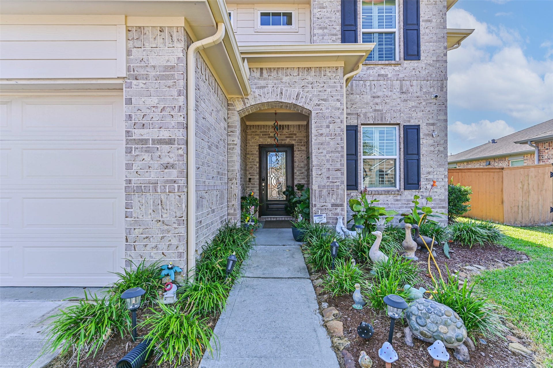 12527 Jetty Cove Drive, Texas City, TX 77568 Inviting covered front entrance featuring an arched brick entry, decorative glass front door, and landscaped walkway.