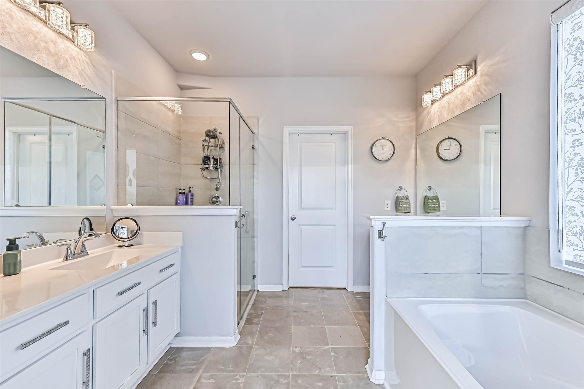 12527 Jetty Cove Drive, Texas City, TX 77568 Wide-angle view of the primary bathroom showcasing the separate soaking tub and glass-enclosed shower, spacious vanity, and tile flooring.