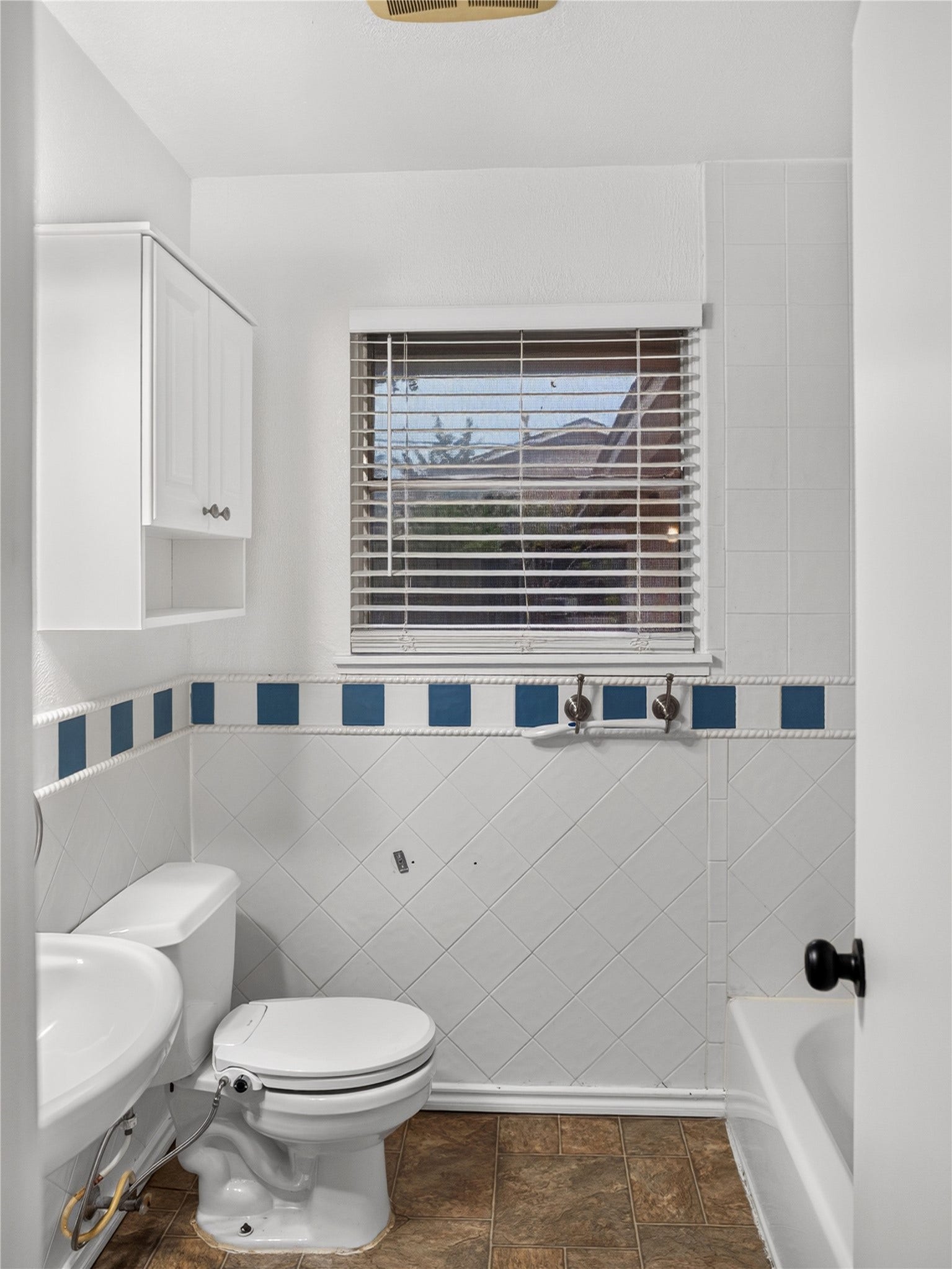 2408 Blueberry Lane, Pasadena, TX 77502 Guest bathroom featuring pedestal sink, decorative tile, and storage cabinet.