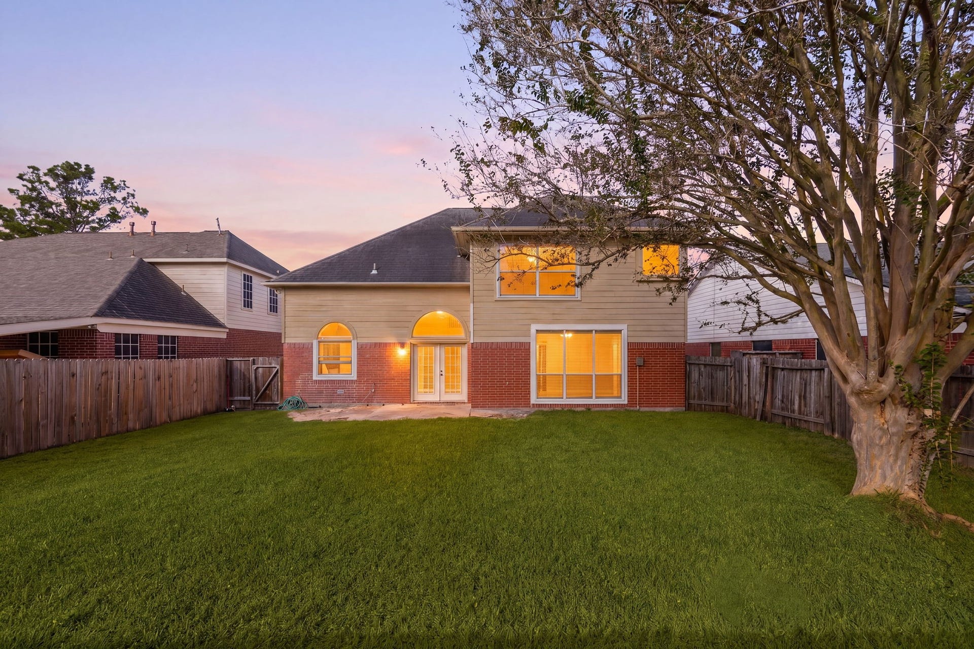 6306 Pago Lane, Houston, TX 77041 As evening falls, the spacious backyard glows beautifully, framed by mature trees and plenty of room to relax or entertain.