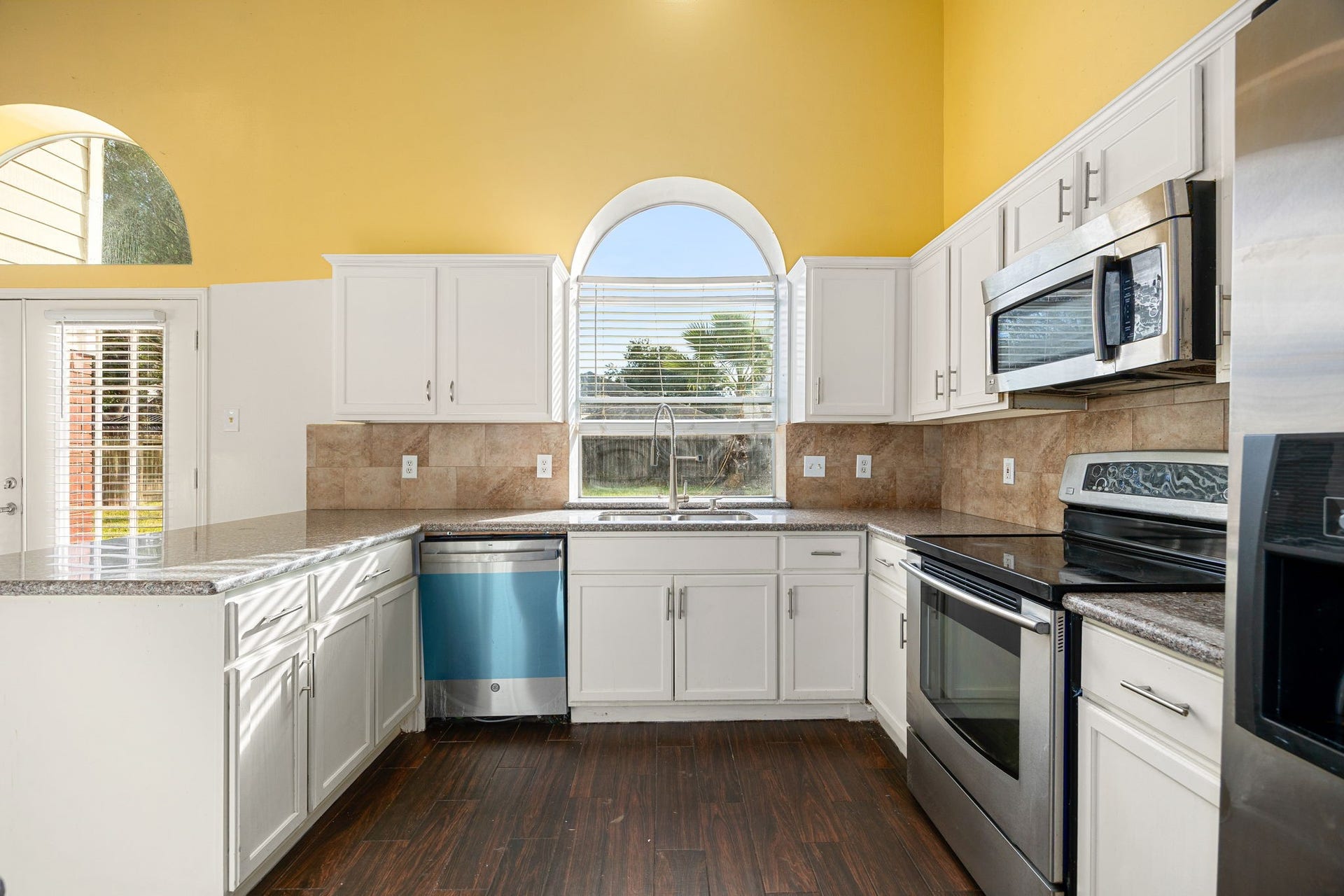 6306 Pago Lane, Houston, TX 77041 The bright kitchen features granite countertops, a tile backsplash, and stainless steel appliances, with a large window overlooking the backyard.