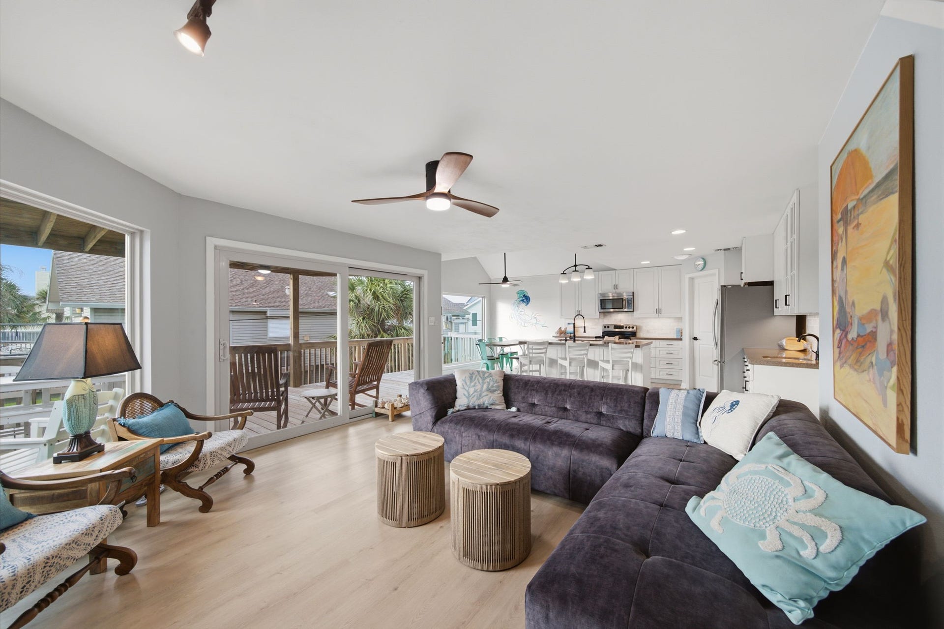 Coming down from the top floor, enter into a spacious living room with walls of windows facing the beach, bathed in natural light all day.