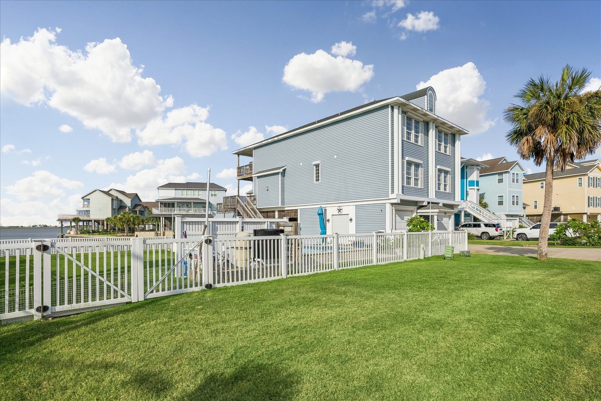 426 Sunset Circle, Tiki Island, TX 77554 Fully fenced yard with new vinyl fencing for enclosure with three new gates & locks. Side view of the home showing the defined outdoor space.
