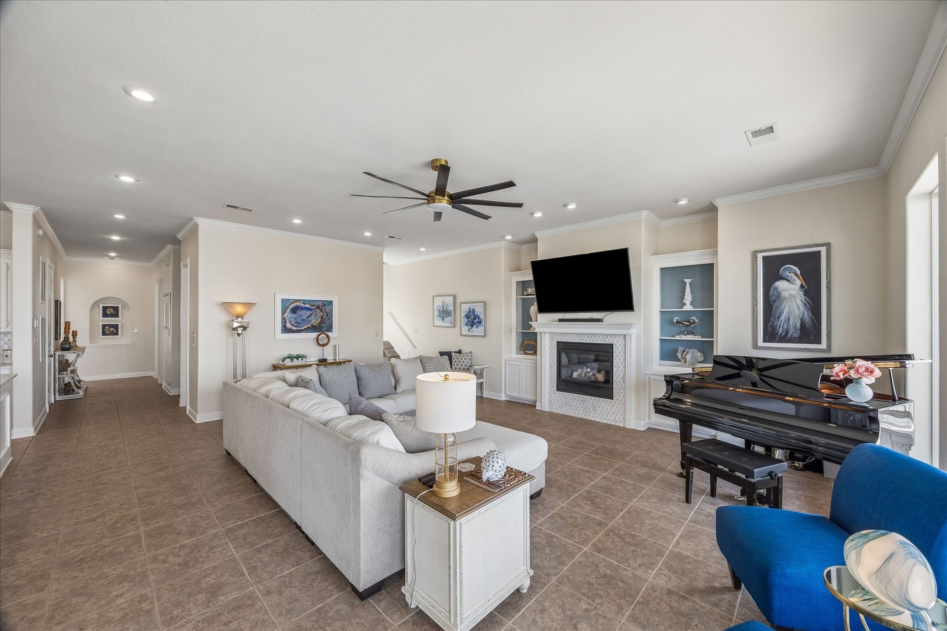 426 Sunset Circle, Tiki Island, TX 77554 Open-concept living room with tiled flooring, crown molding, fireplace with metal surround updated with new trim & quartz, custom built-ins and abundant storage.