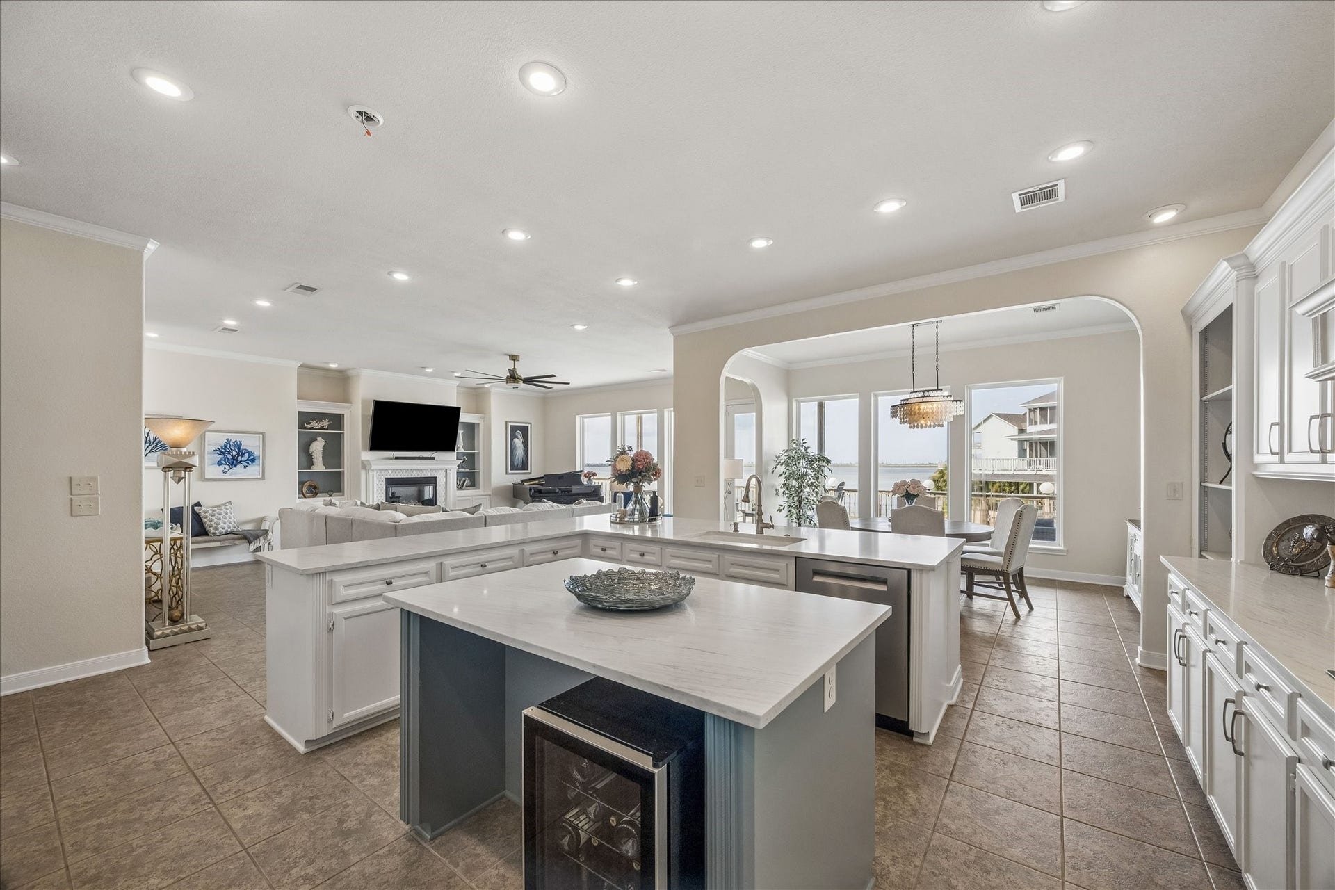426 Sunset Circle, Tiki Island, TX 77554 Open kitchen with tile flooring flowing into the living and dining areas, creating a cohesive entertaining space. A large walk-in pantry offers abundant storage, additional shelving, and a built-in spice rack. Additional features include a beverage refrigerator, abundant cabinetry, and easy access to the waterfront views.